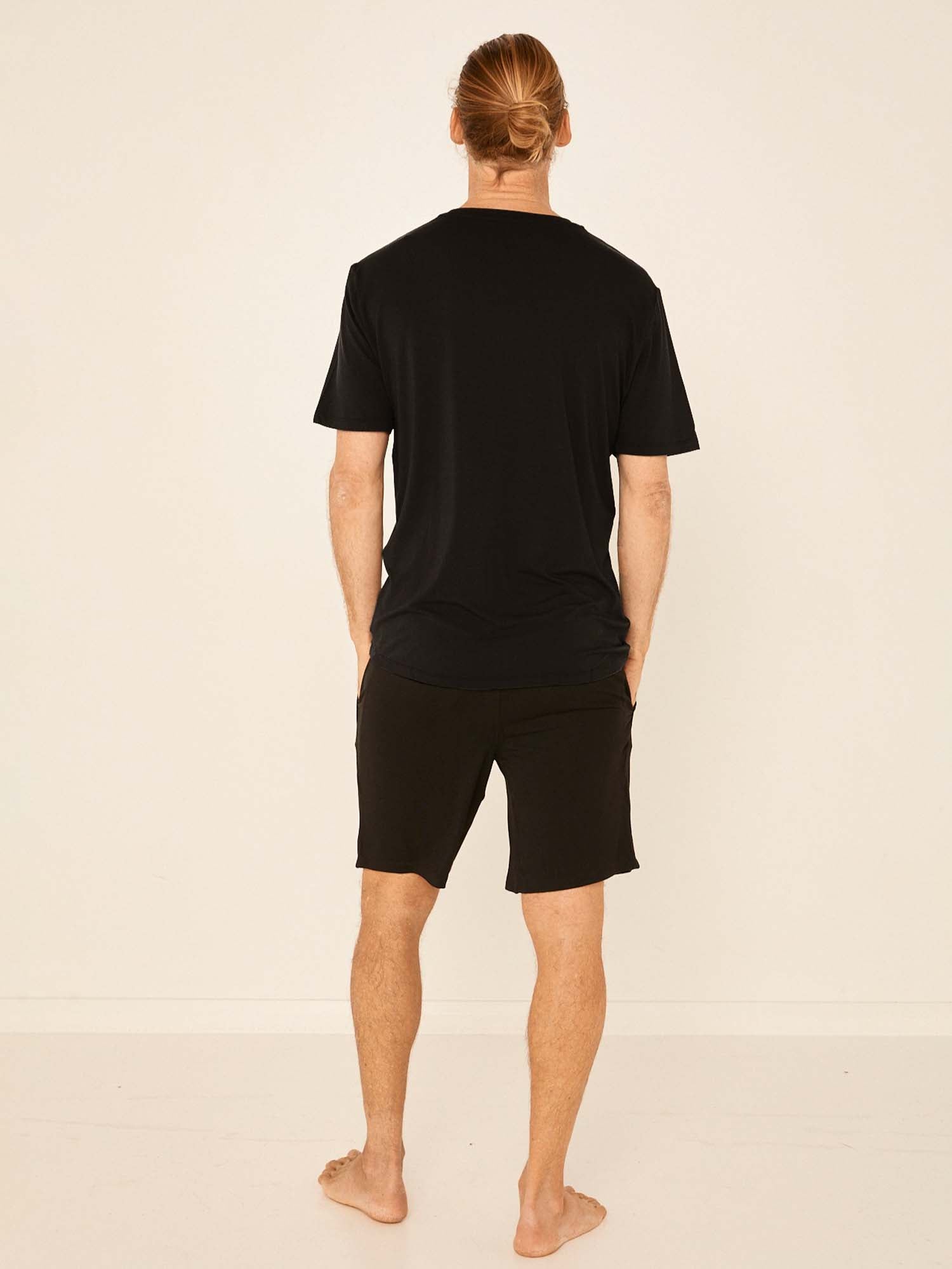 Male model wearing black casual shorts, above knee length with fly front detailing, pockets and elasticised waistband, men's bamboo clothing