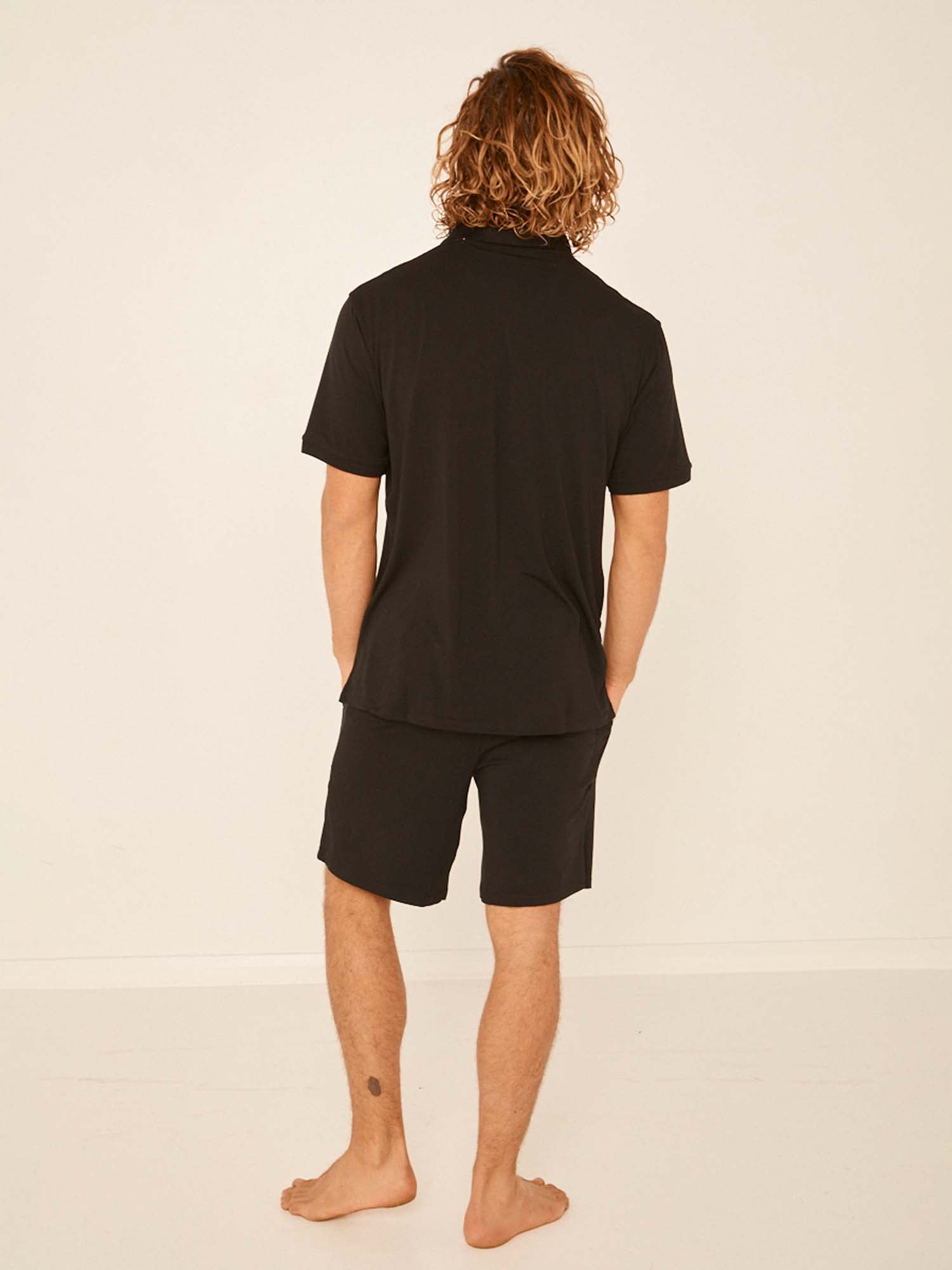 Male model wearing black casual shorts, above knee length with fly front detailing, pockets and elasticised waistband, men's bamboo clothing