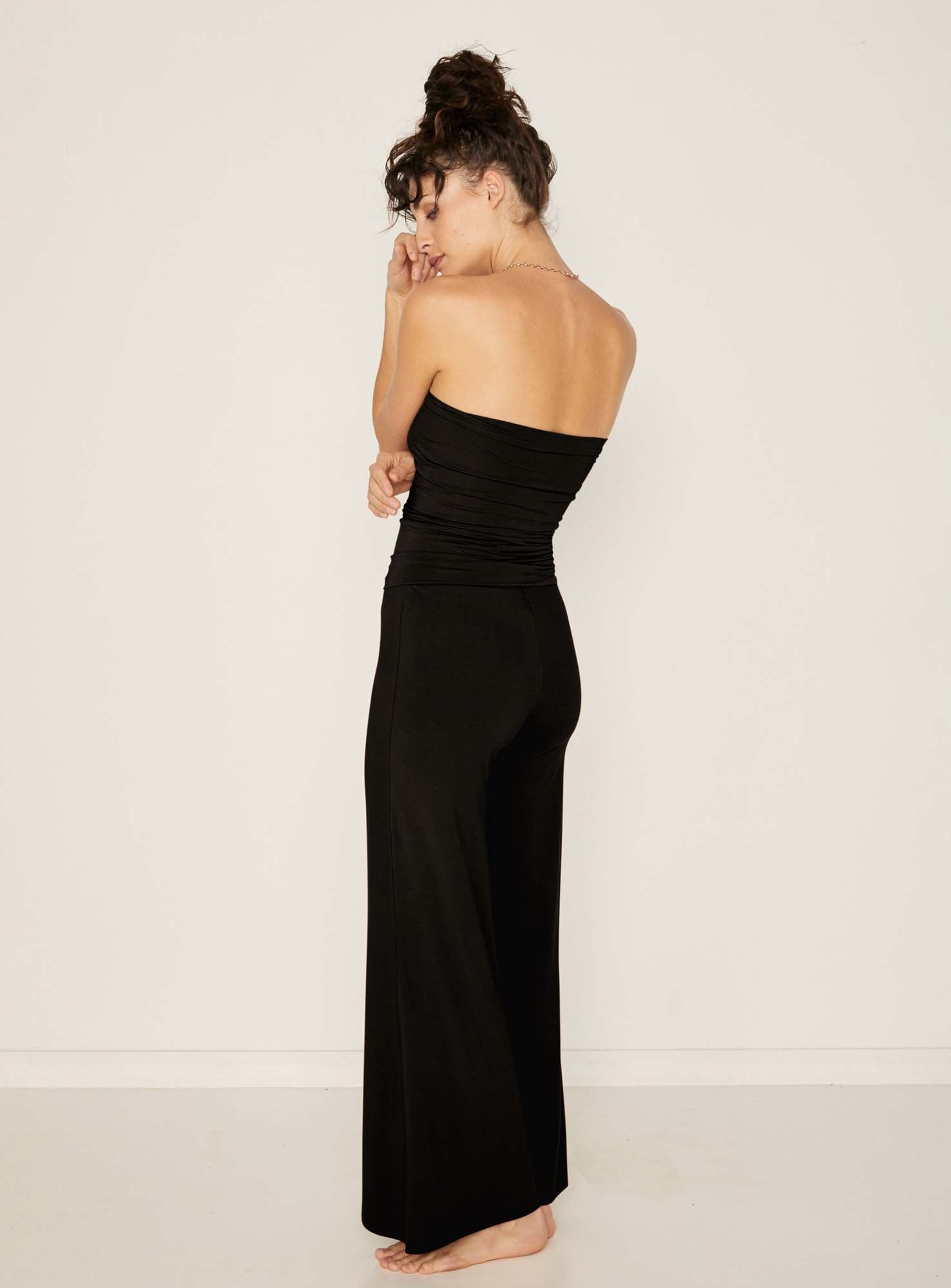 Model wearing black full length palazzo pants, fitted waist and hips with flowing wide leg, adjustible high waistband, women's bamboo clothing