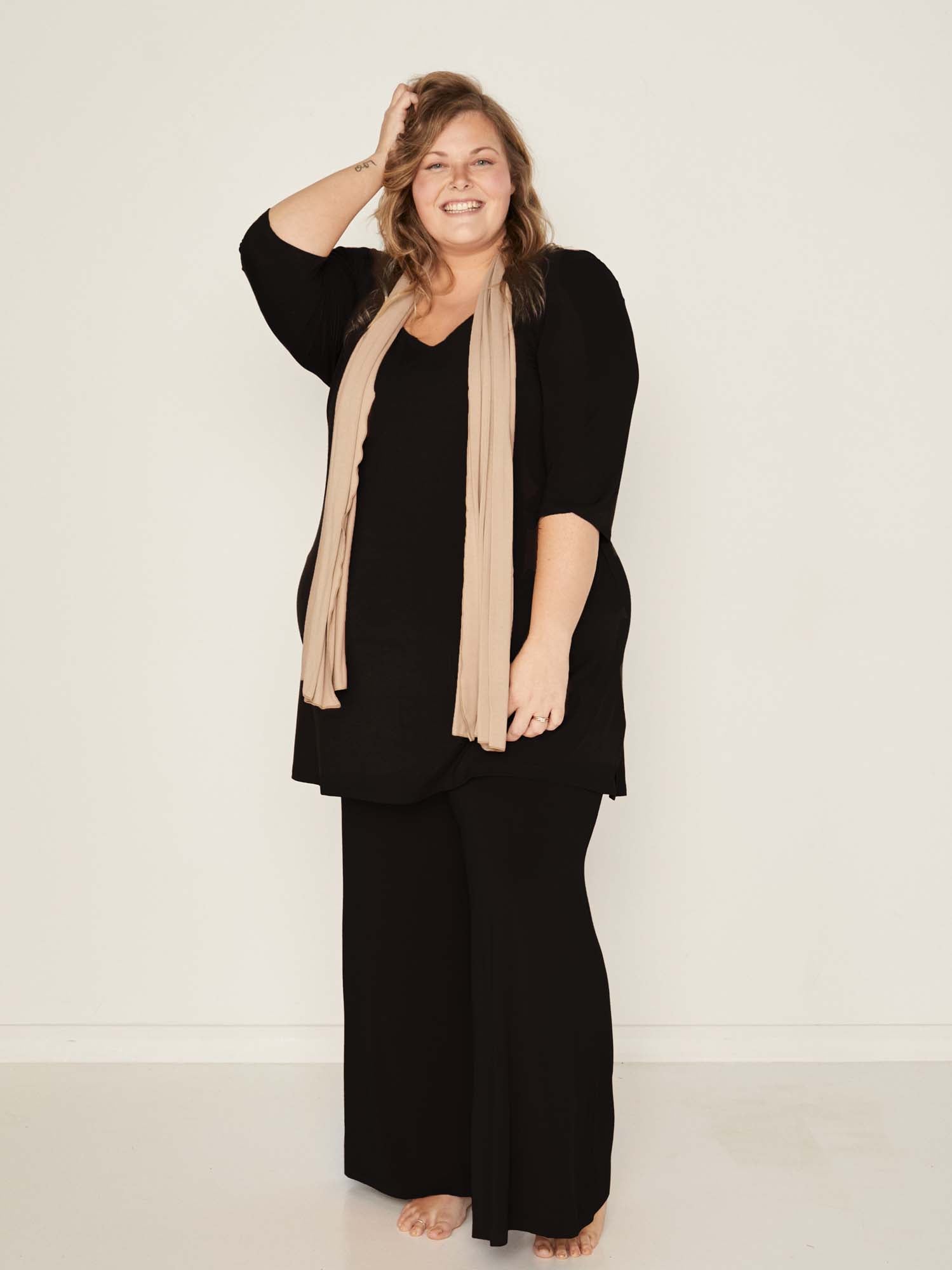 Model wearing black full length palazzo pants, fitted waist and hips with flowing wide leg, adjustible high waistband, women's bamboo clothing