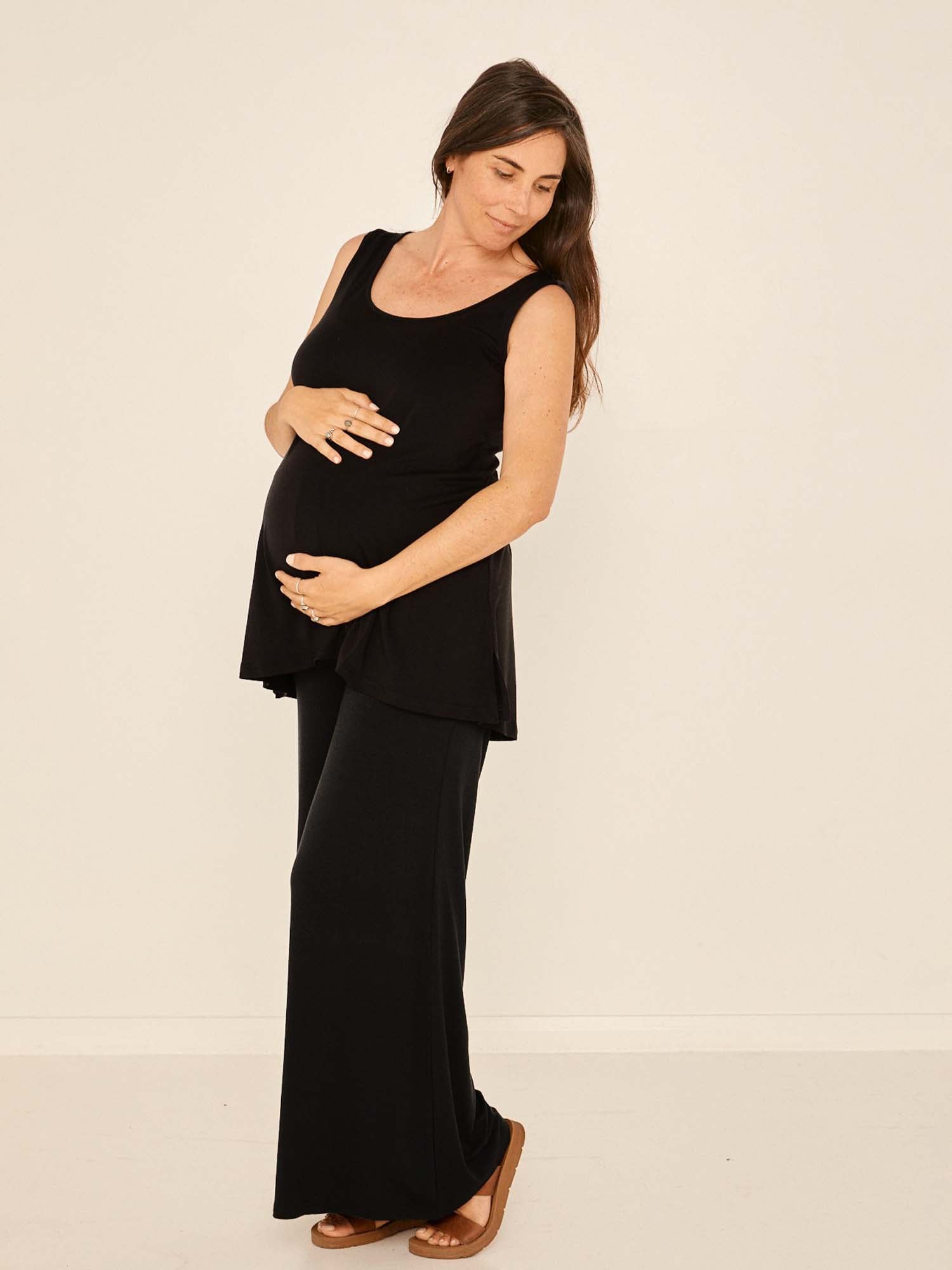 Model wearing black full length palazzo pants, fitted waist and hips with flowing wide leg, adjustible high waistband, women's bamboo clothing