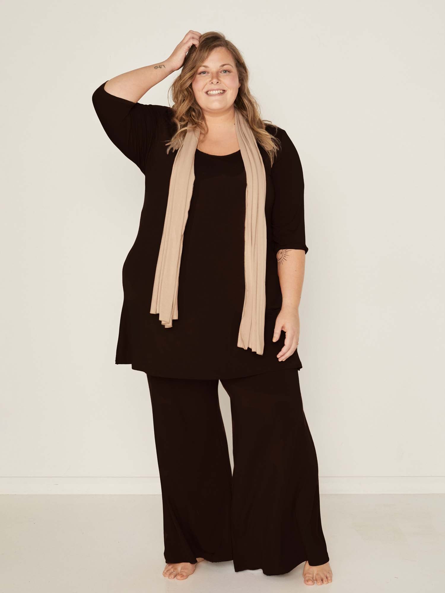 Model wearing black full length palazzo pants, fitted waist and hips with flowing wide leg, adjustible high waistband, women's bamboo clothing