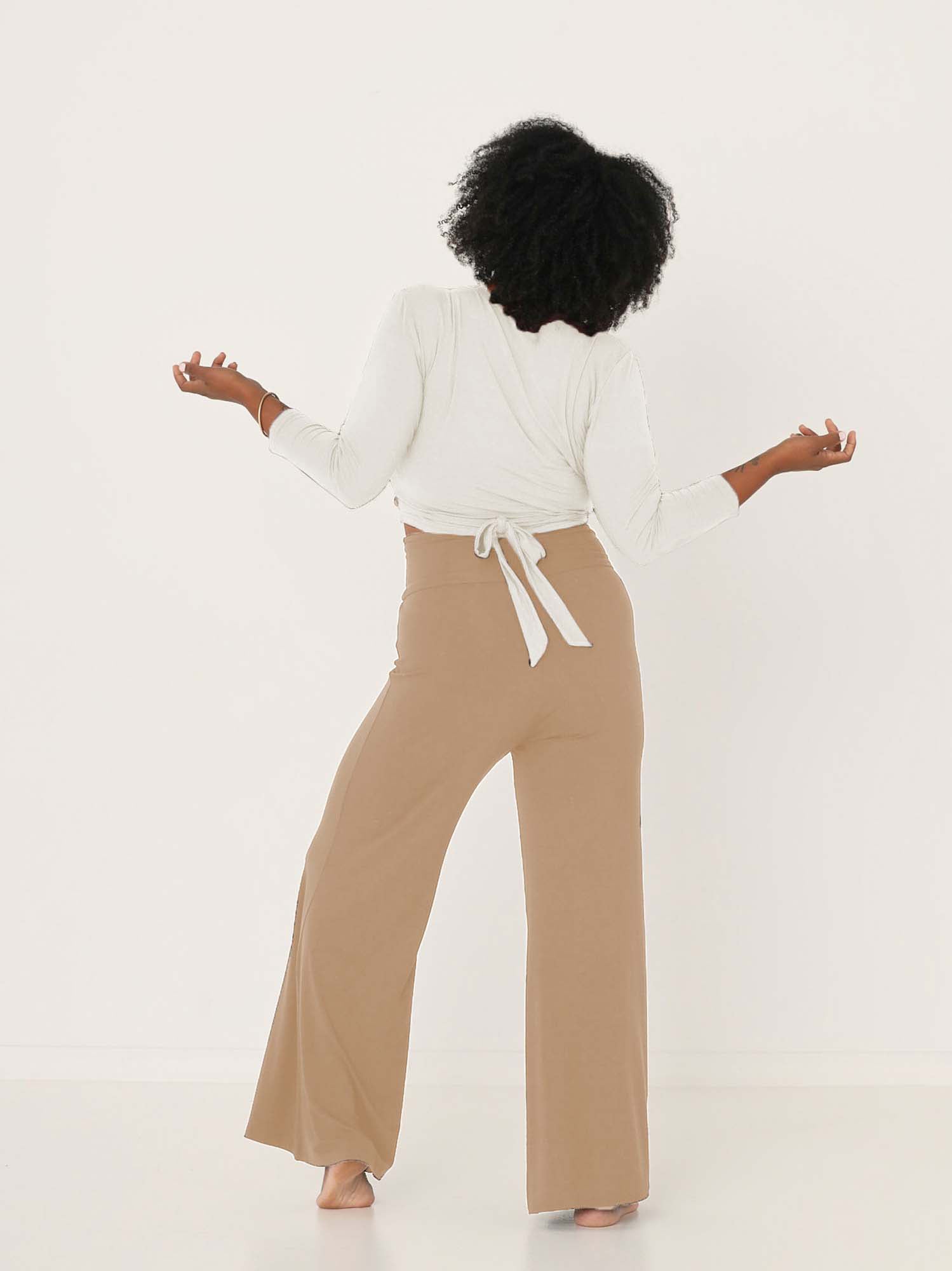 Model wearing caramel full length palazzo pants, fitted waist and hips with flowing wide leg, adjustable high waistband, women's bamboo clothing