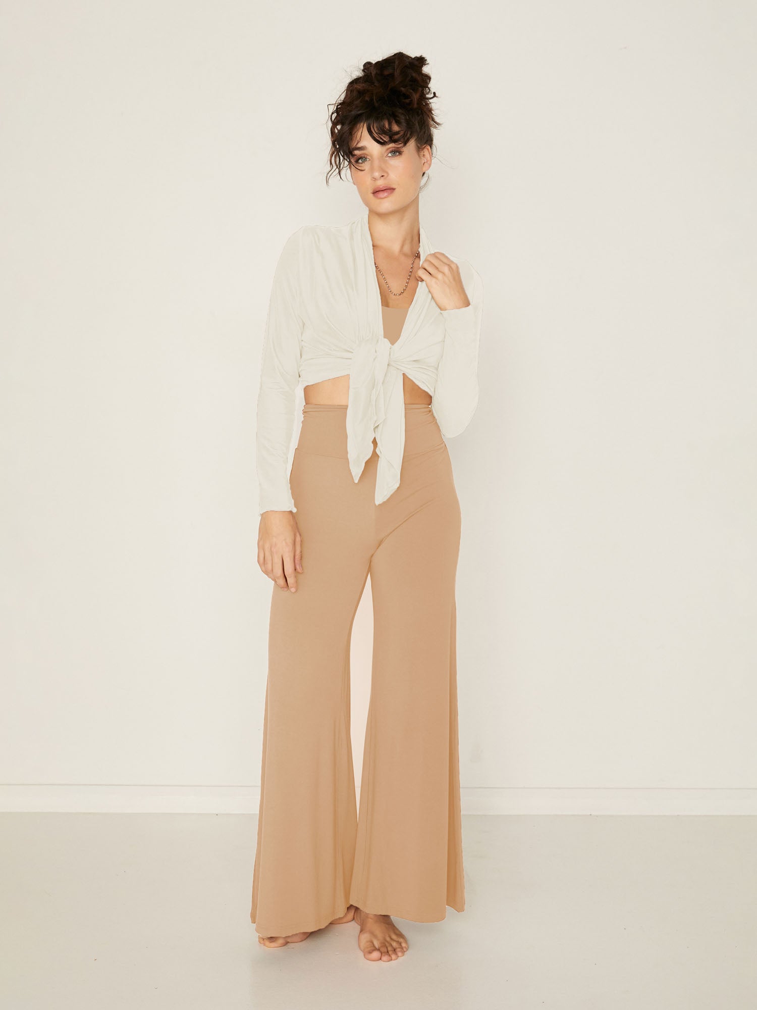 Model wearing black full length palazzo pants, fitted waist and hips with flowing wide leg, adjustable high waistband, women's bamboo clothing