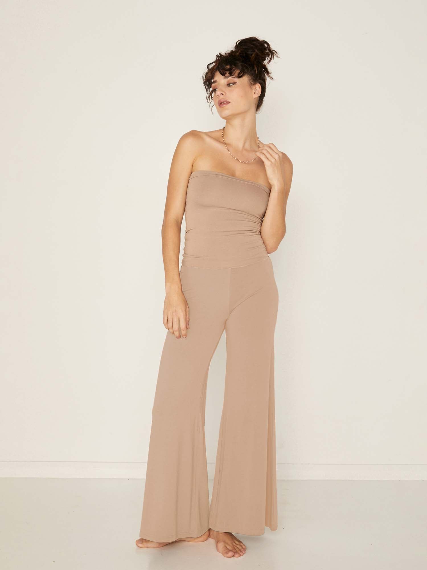 Model wearing caramel full length palazzo pants, fitted waist and hips with flowing wide leg, adjustible high waistband, women's bamboo clothing