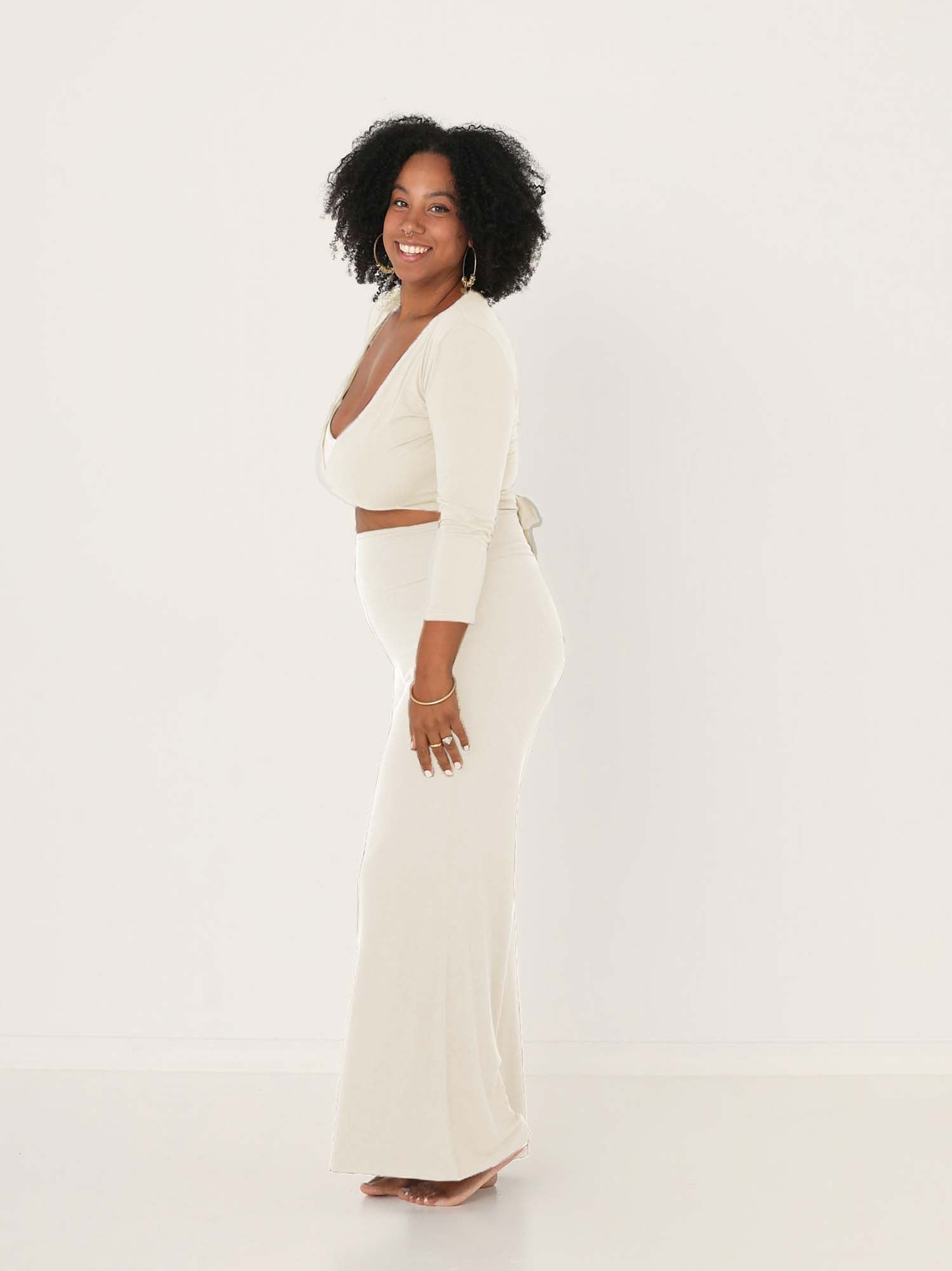 Model wearing cream full length palazzo pants, fitted waist and hips with flowing wide leg, adjustible high waistband, women's bamboo clothing