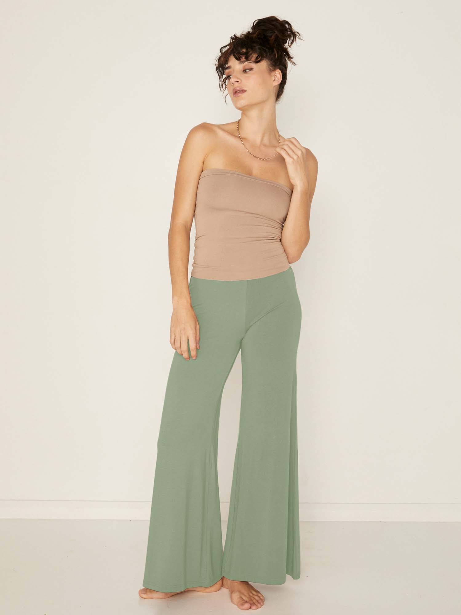Model wearing eucalyptus full length palazzo pants, fitted waist and hips with flowing wide leg, adjustible high waistband, women's bamboo clothing