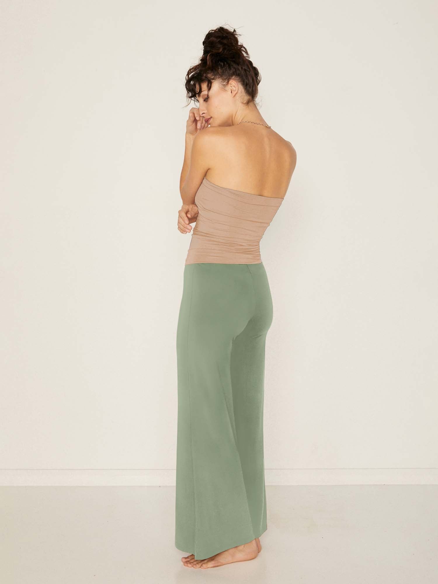 Model wearing eucalyptus full length palazzo pants, fitted waist and hips with flowing wide leg, adjustible high waistband, women's bamboo clothing