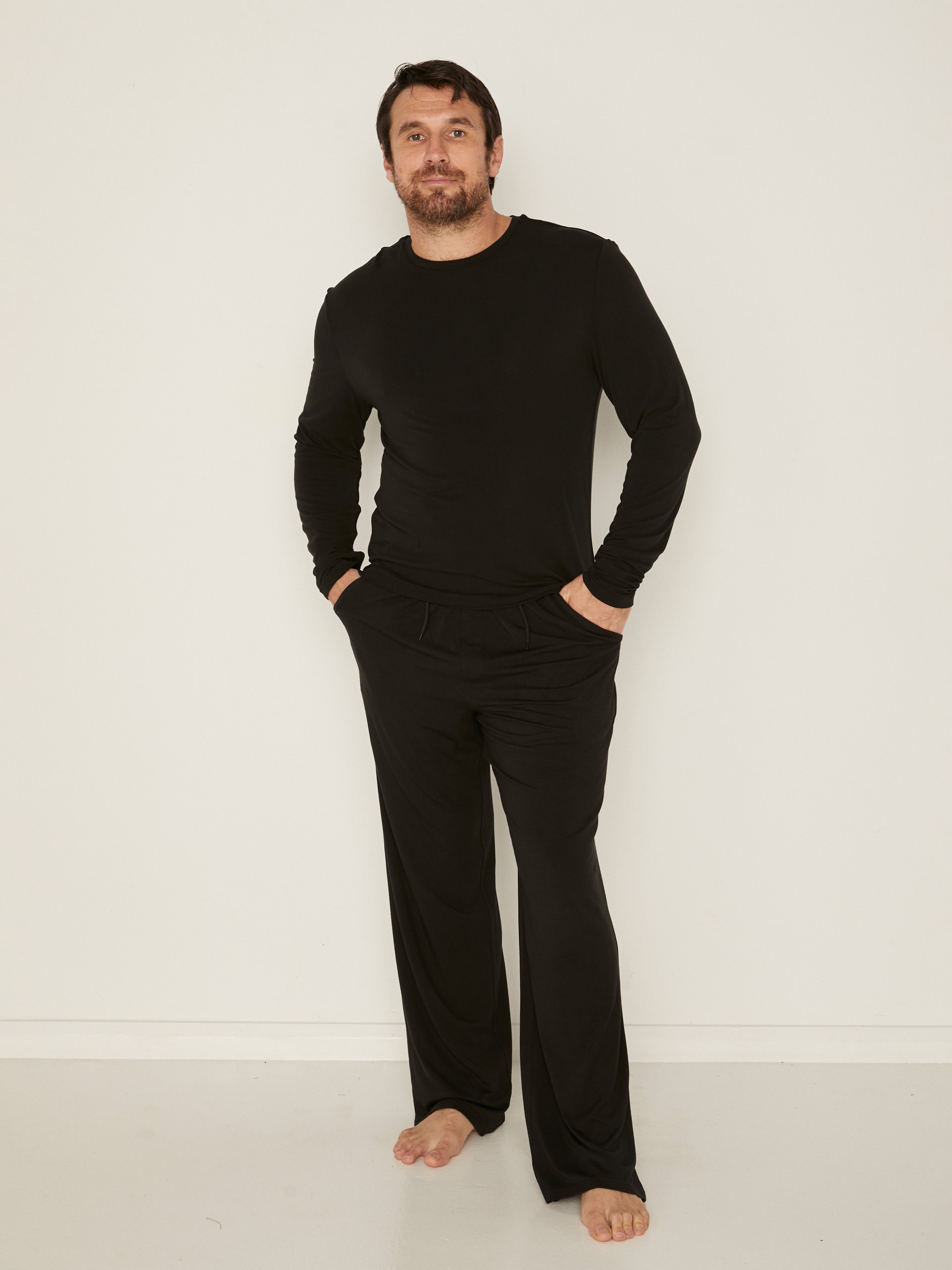 Male model full length black casual pants with elasticised waist, relaxed loose leg and deep pockets, men's bamboo clothing
