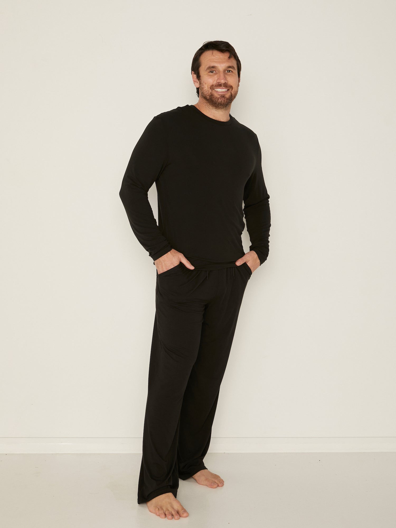 Male model full length black casual pants with elasticised waist, relaxed loose leg and deep pockets, men's bamboo clothing