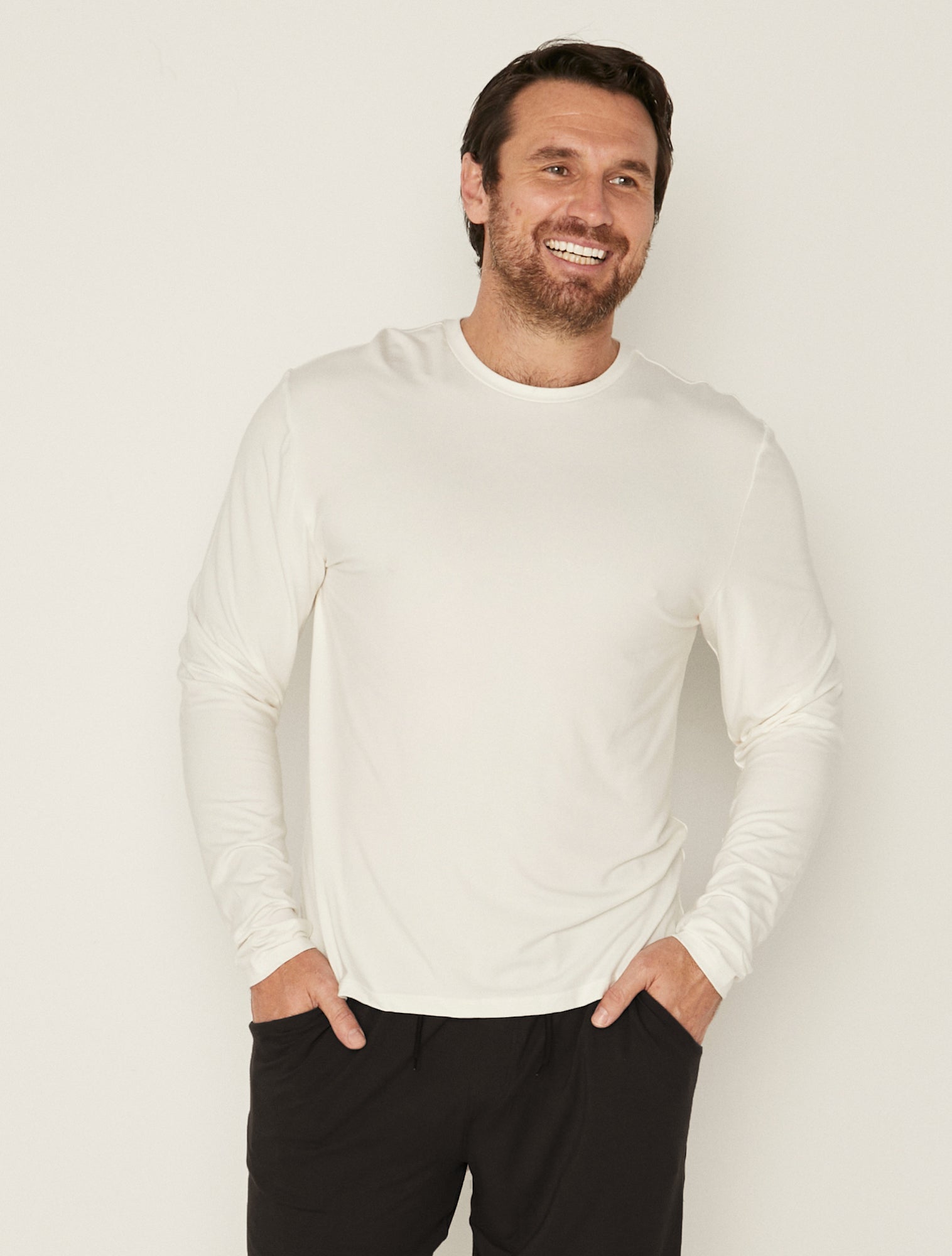 Male model wearing cream classic long sleeve t-shirt, generous fit, soft neckband, crew neckline, men's bamboo clothing