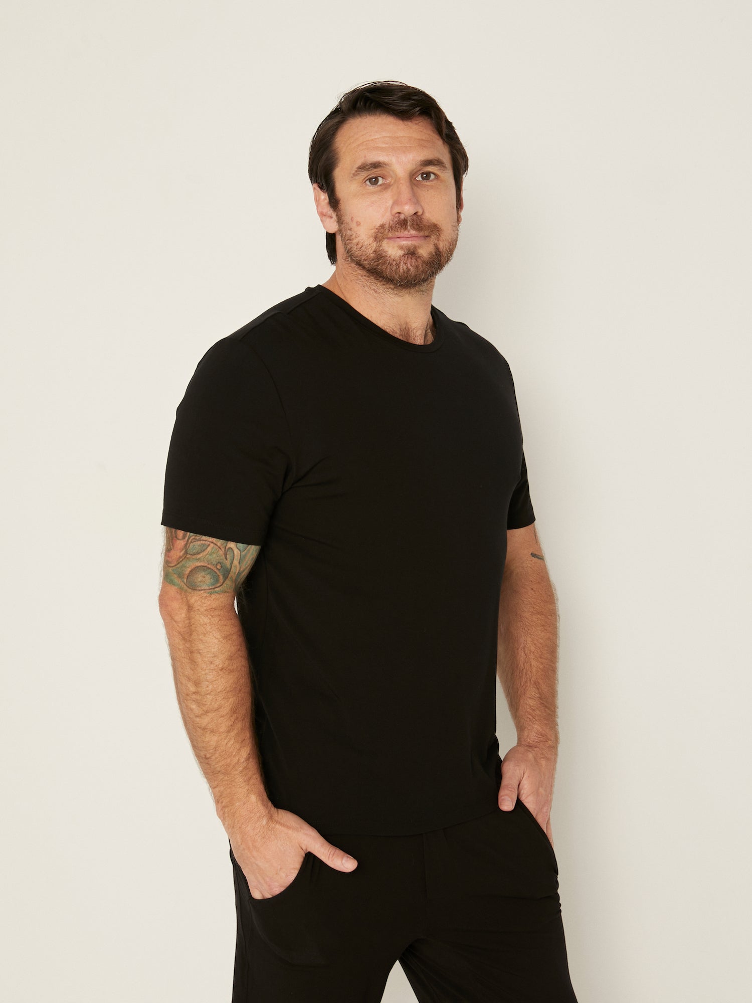Male model wearing black generous classic fit tee, soft neckband, crew neckline, short sleeve, men's bamboo clothing