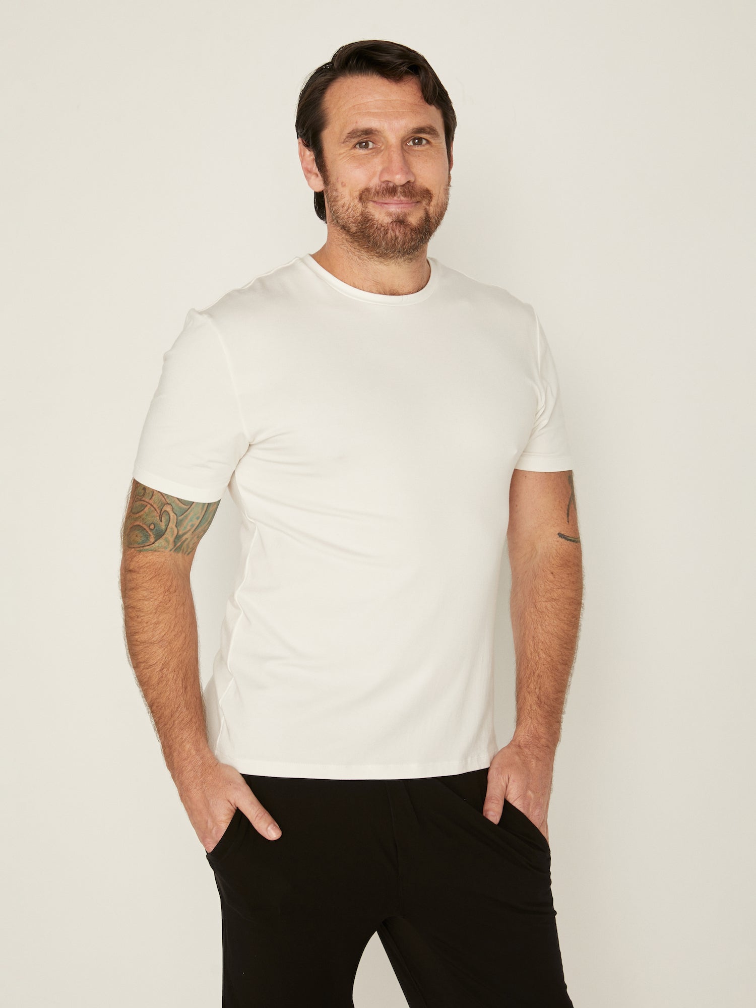 Male model wearing cream generous classic fit tee, soft neckband, crew neckline, short sleeve, men's bamboo clothing