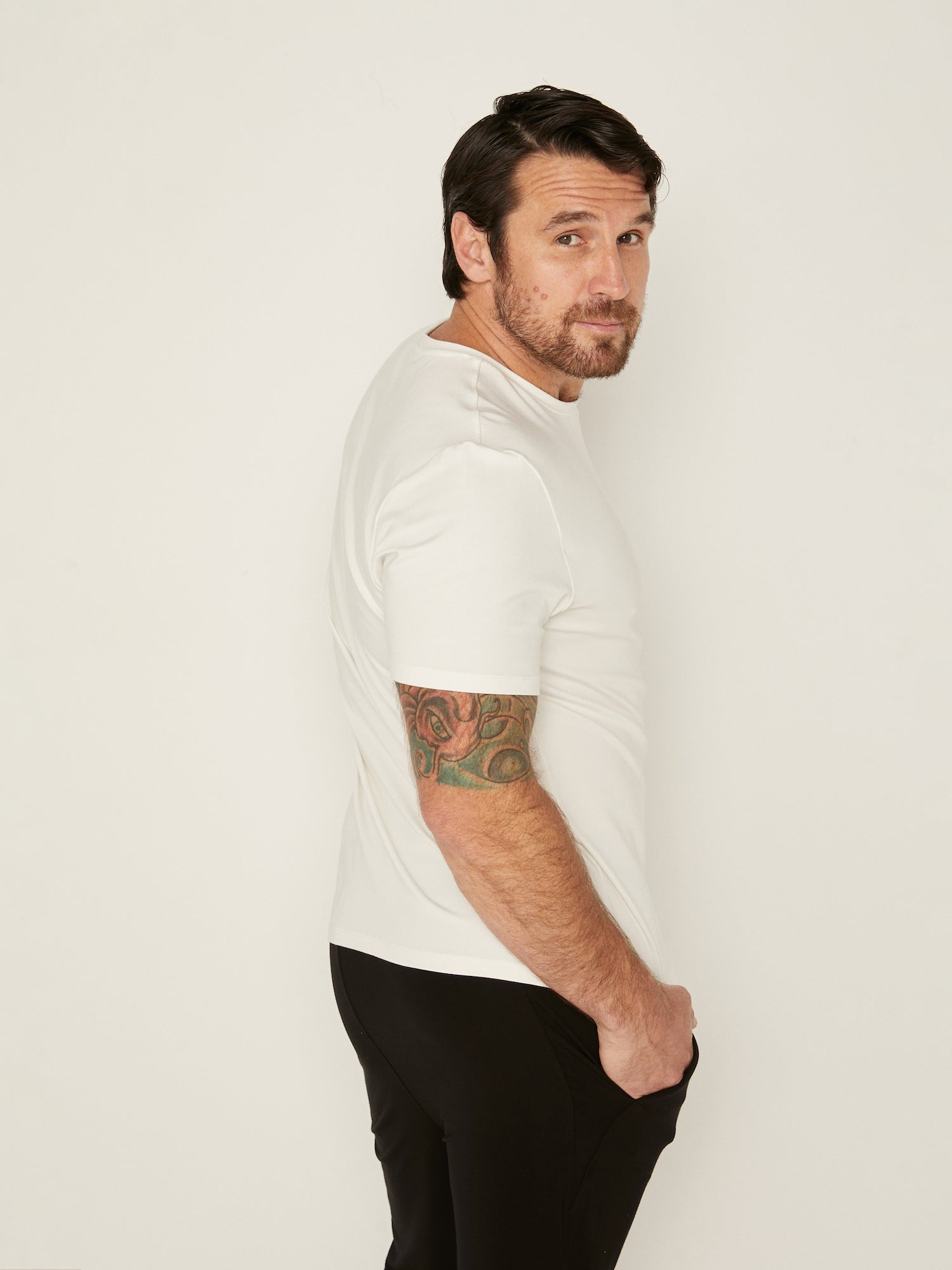 Male model wearing cream generous classic fit tee, soft neckband, crew neckline, short sleeve, men's bamboo clothing