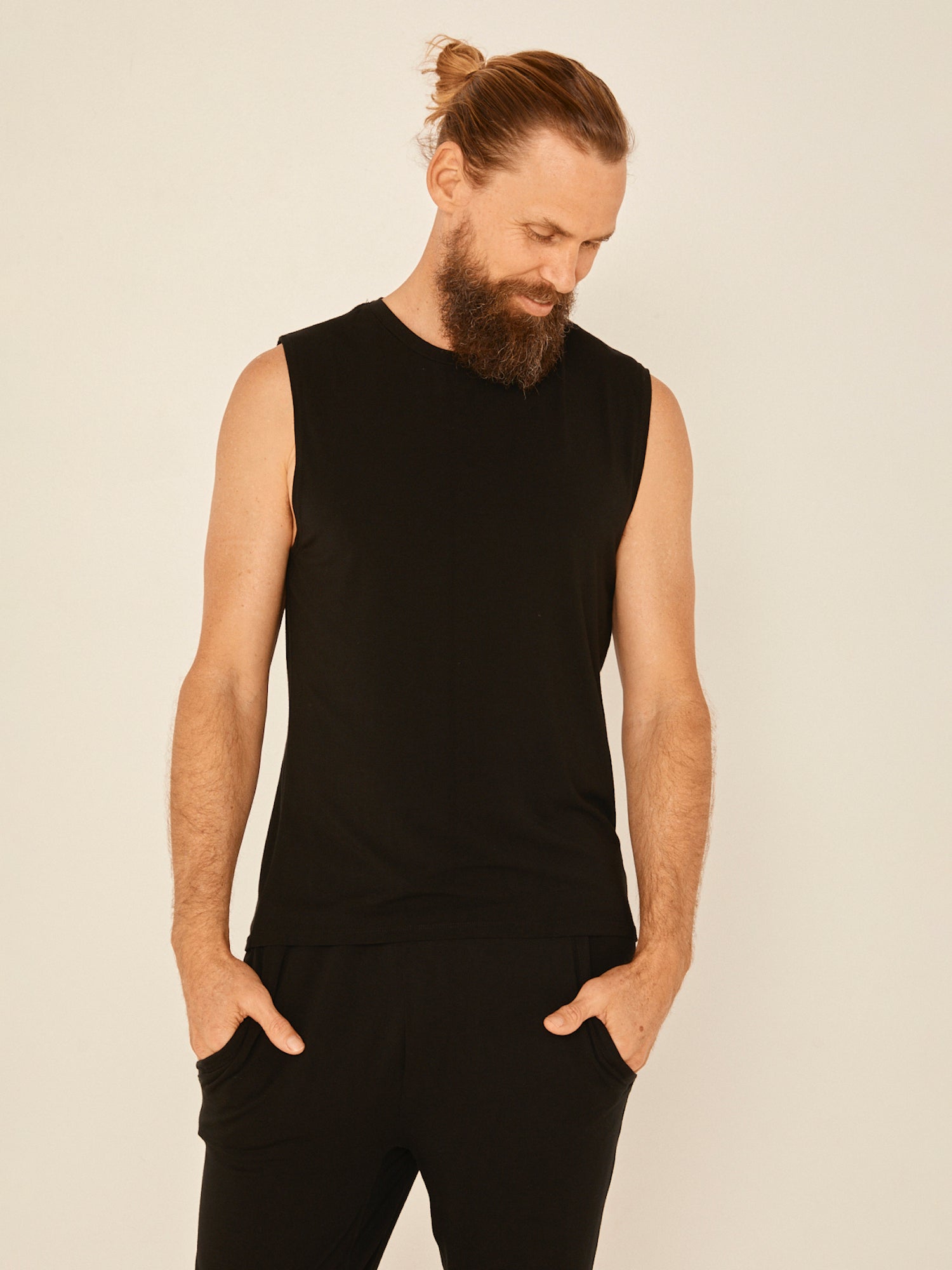 Male model wearing black generous classic fit tank singlet, soft neckband, crew neckline, sleeveless, men's bamboo clothing