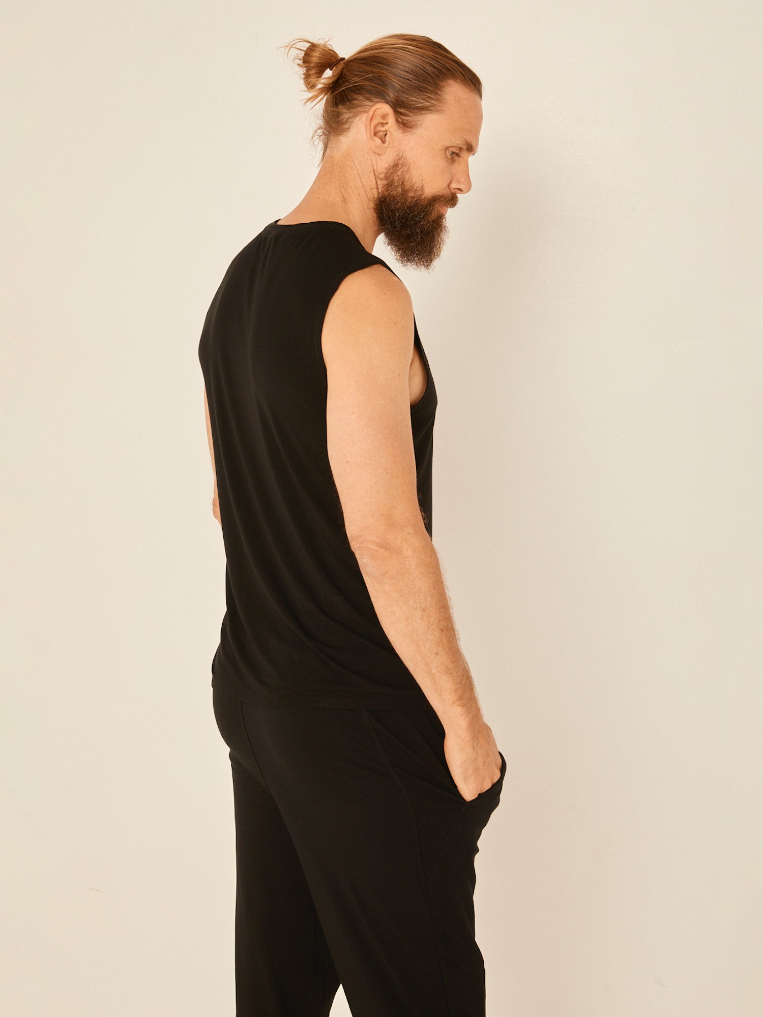 Male model wearing black generous classic fit tank singlet, soft neckband, crew neckline, sleeveless, men's bamboo clothing