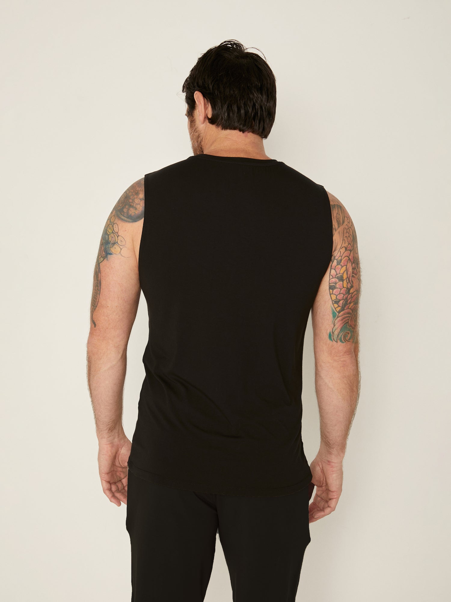 Male model wearing black generous classic fit tank singlet, soft neckband, crew neckline, sleeveless, men's bamboo clothing