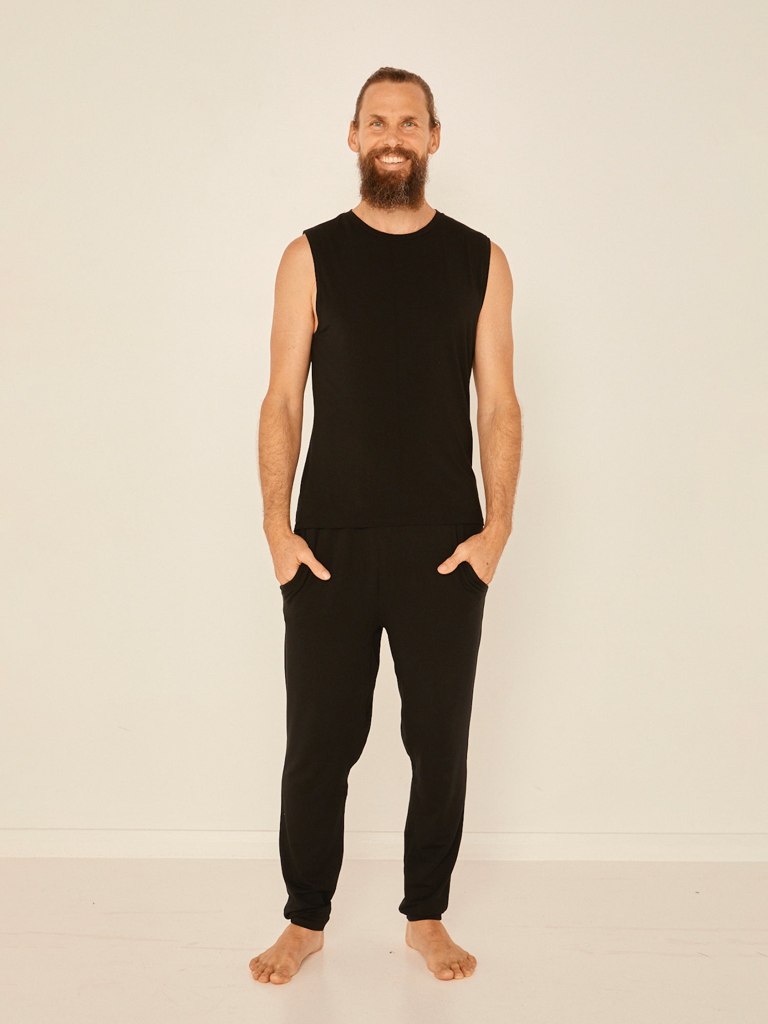 Male model wearing black generous classic fit tank singlet, soft neckband, crew neckline, sleeveless, men's bamboo clothing