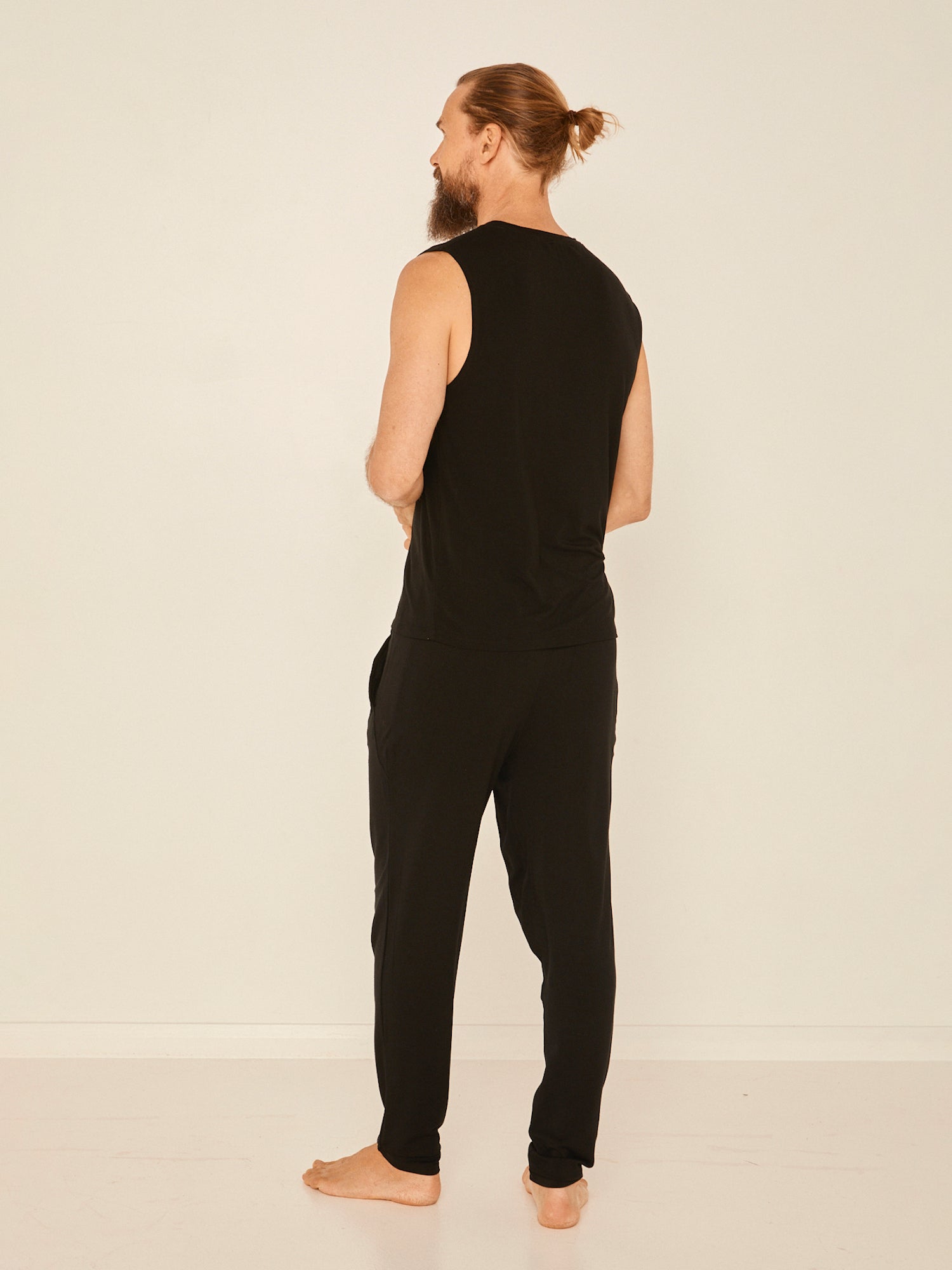 Male model wearing black generous classic fit tank singlet, soft neckband, crew neckline, sleeveless, men's bamboo clothing