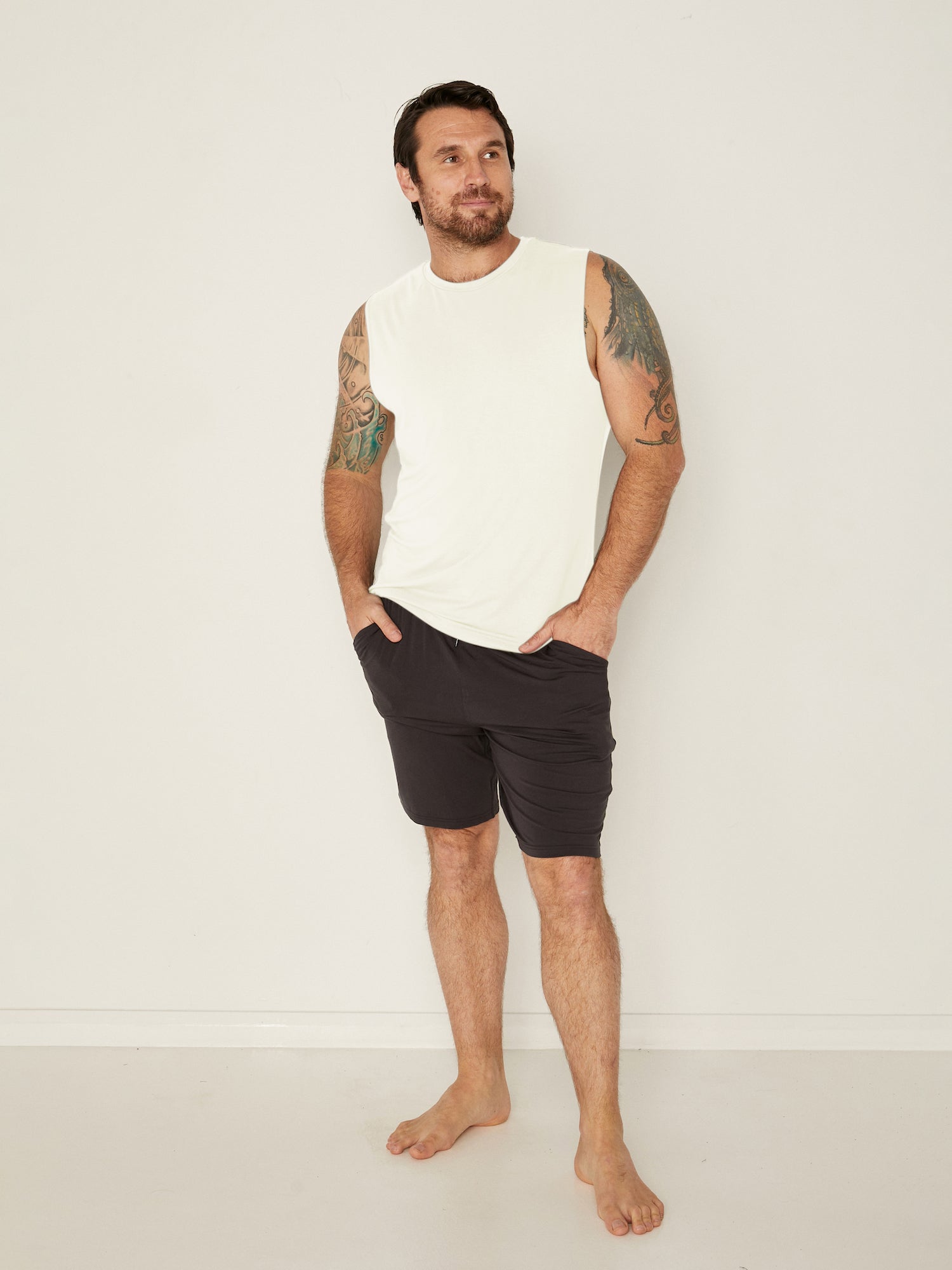 Male model wearing cream generous classic fit tank singlet, soft neckband, crew neckline, sleeveless, men's bamboo clothing