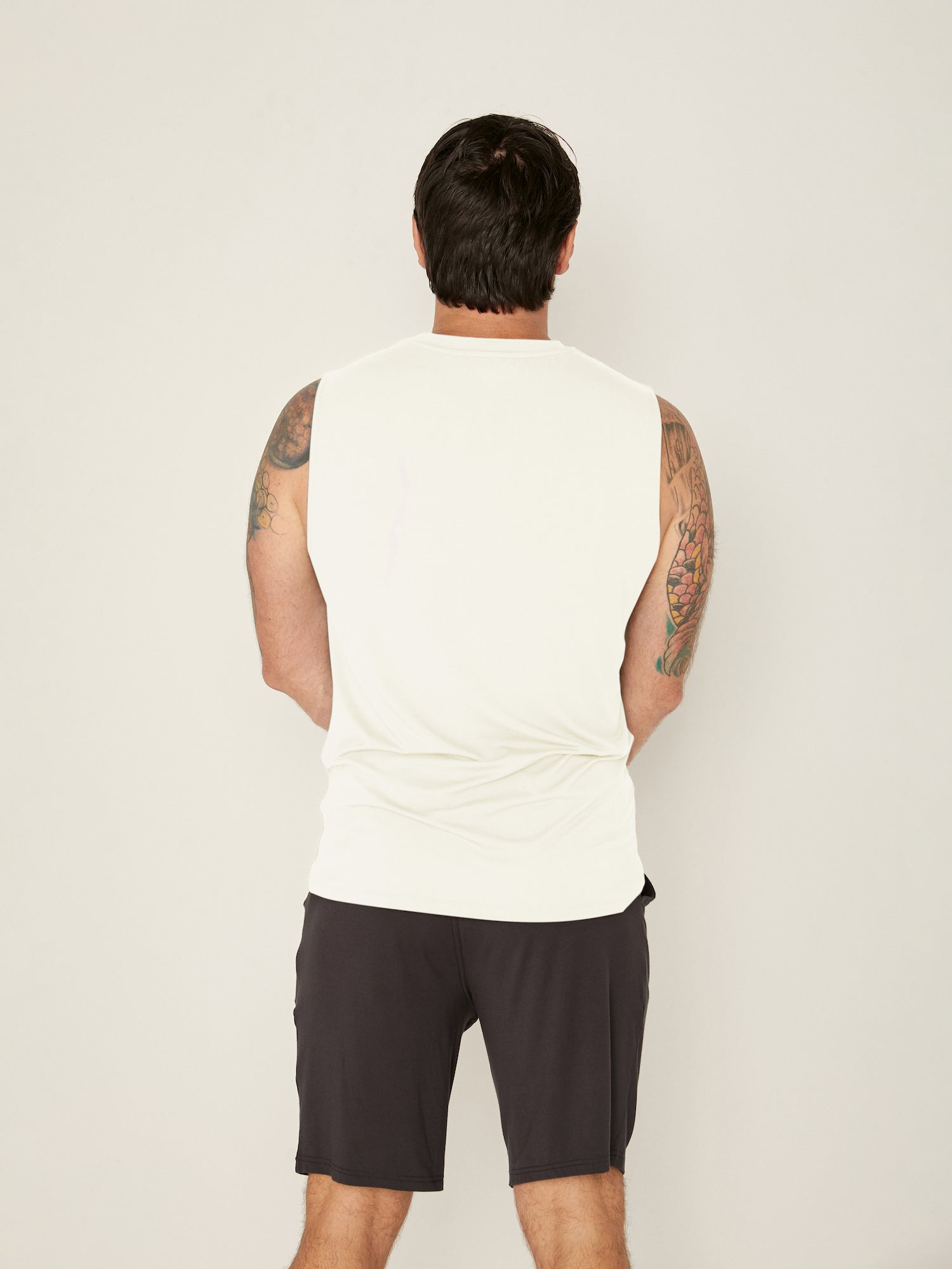 Male model wearing cream generous classic fit tank singlet, soft neckband, crew neckline, sleeveless, men's bamboo clothing