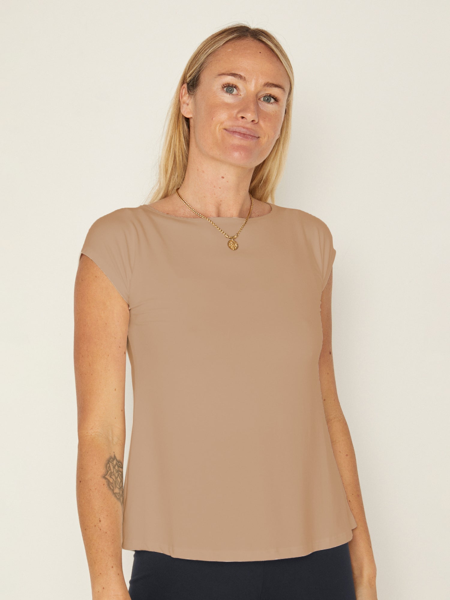 Model wearing a caramel boat neck t-shirt with capped sleeves, fitted through shoulders and chest with loose fit to waist, women's bamboo clothing