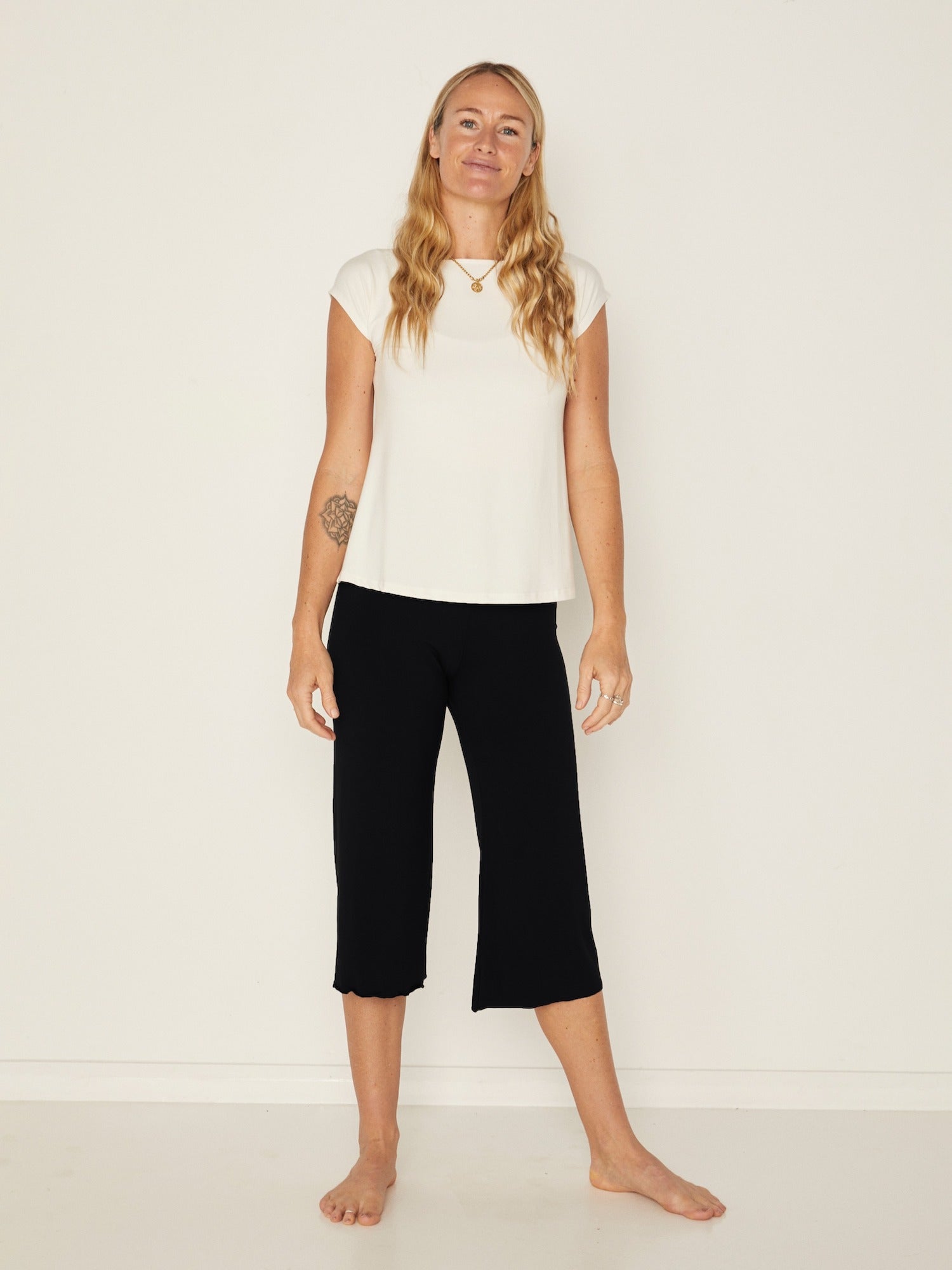 Model wearing a cream boat neck t-shirt with capped sleeves, fitted through shoulders and chest with loose fit to waist, women's bamboo clothing