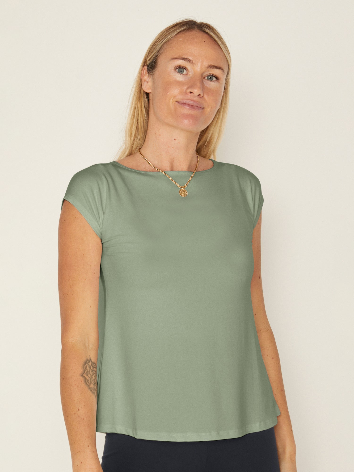 Model wearing a eucalyptus green boat neck t-shirt with capped sleeves, fitted through shoulders and chest with loose fit to waist, women's bamboo clothing