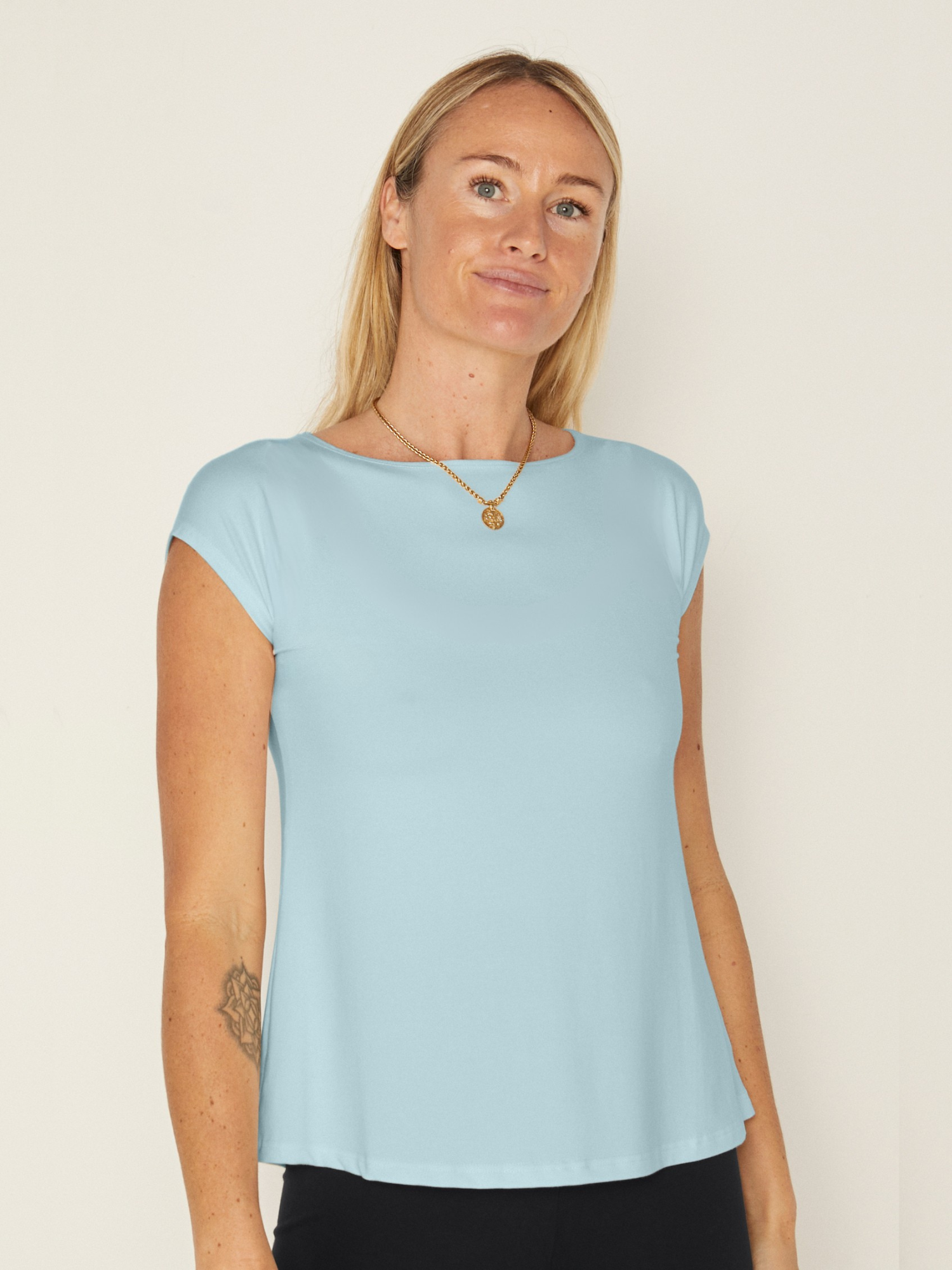 Woman wearing a bamboo topaz blue boat neck t-shirt against a plain background