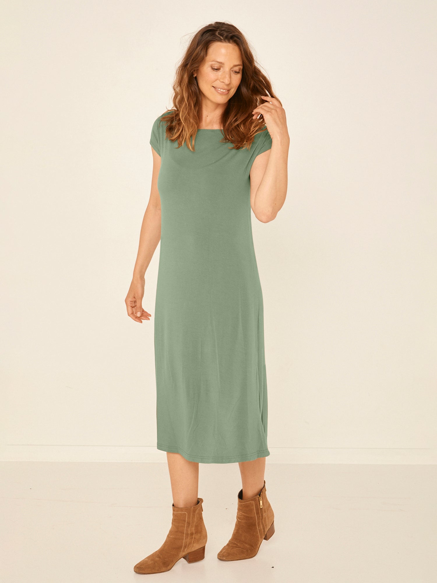 Model wearing a eucalyptus green boat neck dress with capped sleeves, fitted through shoulders and chest and a slight a-line flare to below the knee, women's bamboo clothing