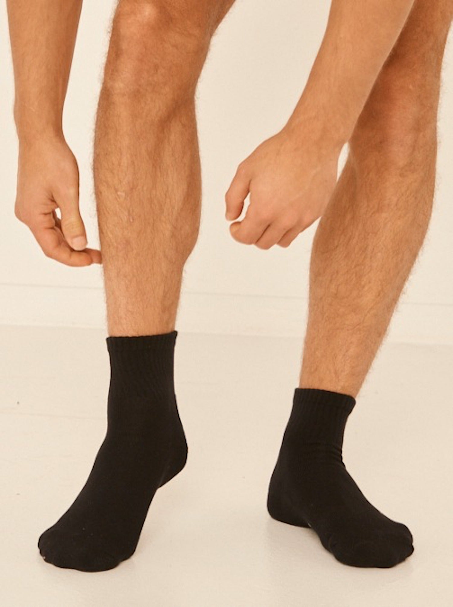 Model wearing black bamboo crew socks, mid to low rise, ribbed ankle support and cushioned sole, bamboo sport sock