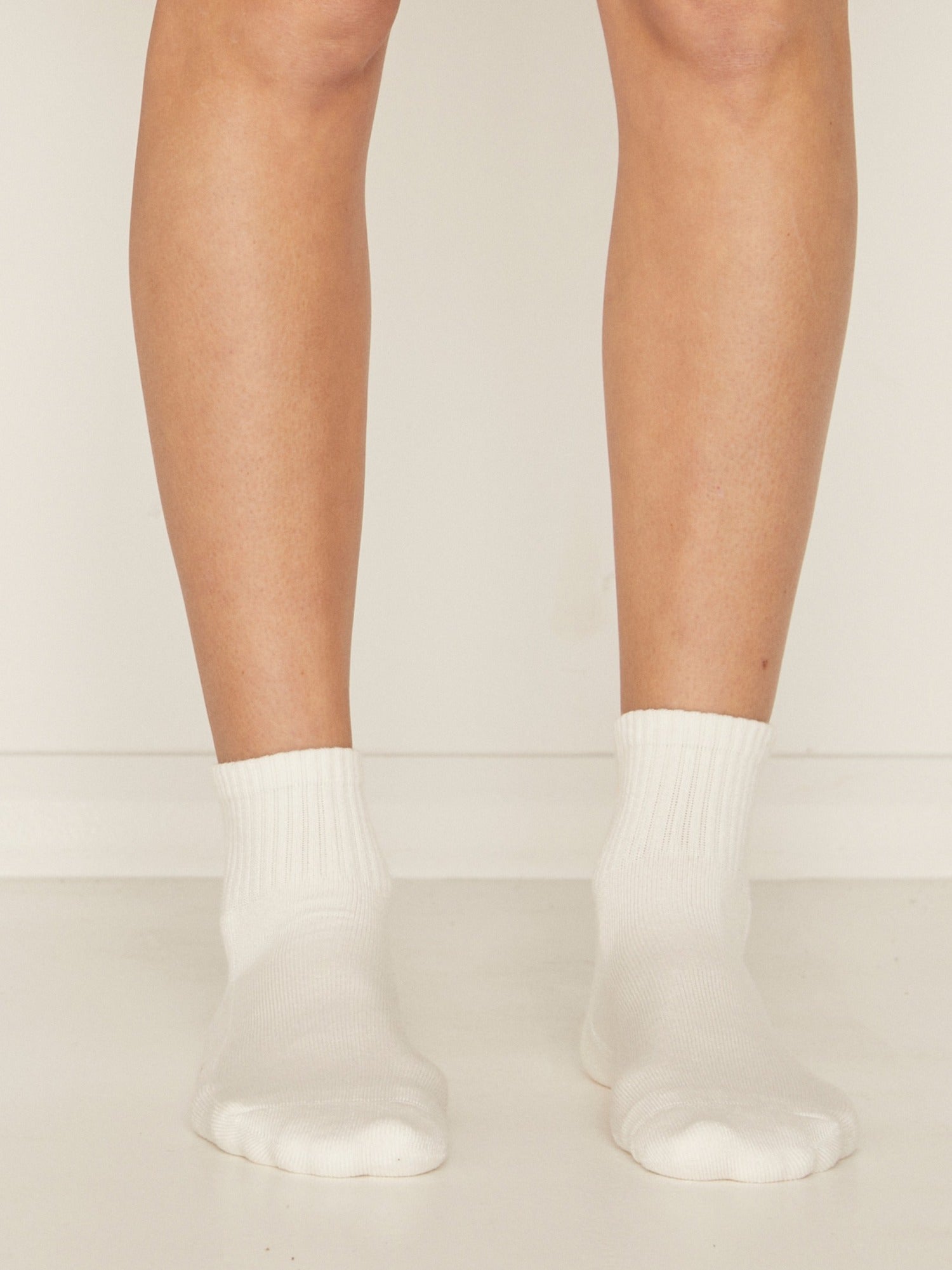 Model wearing white bamboo crew socks, mid to low rise, ribbed ankle support and cushioned sole, bamboo sport sock
