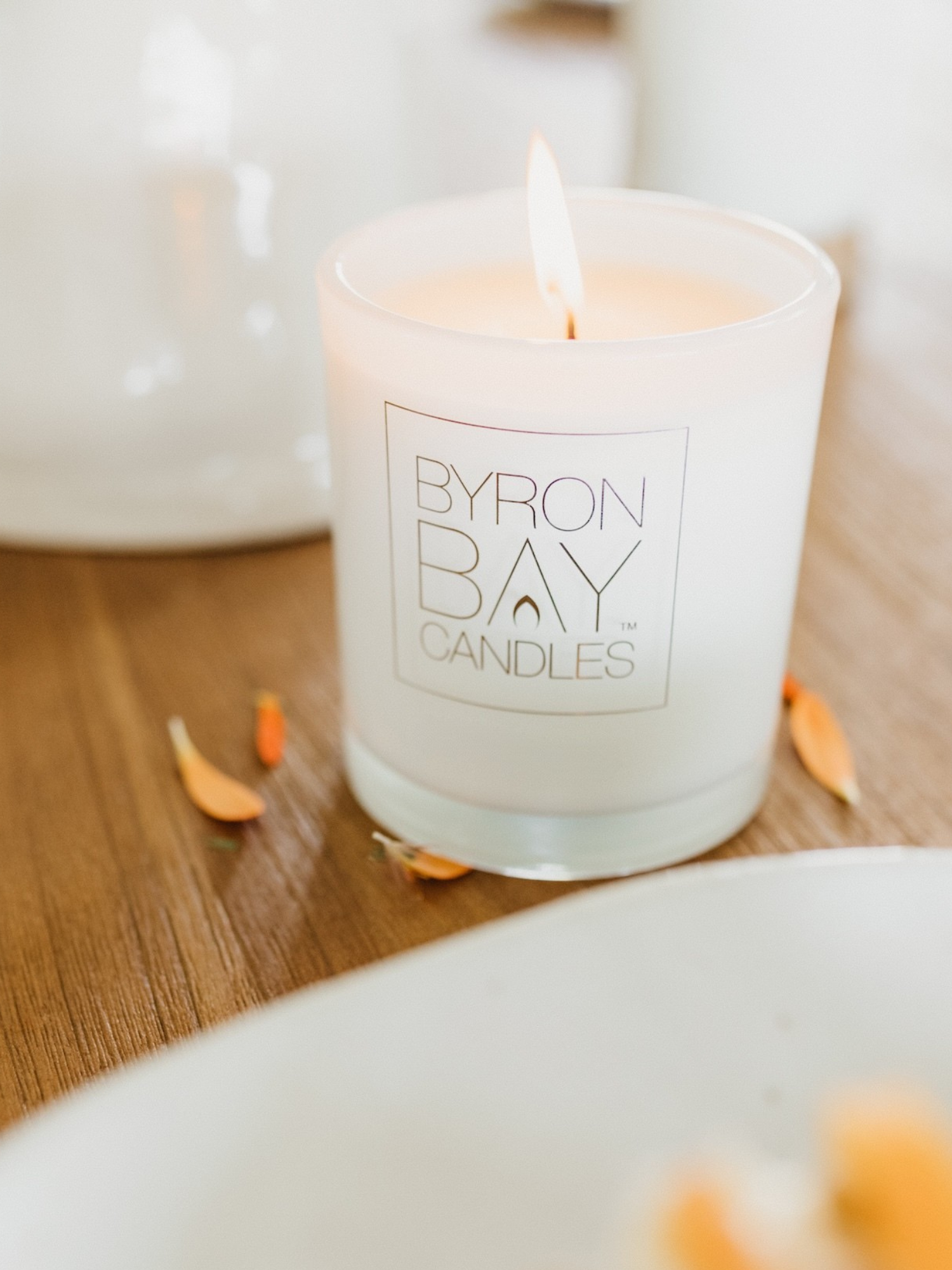 Candle with Byron Bay Candles logo on a wooden surface