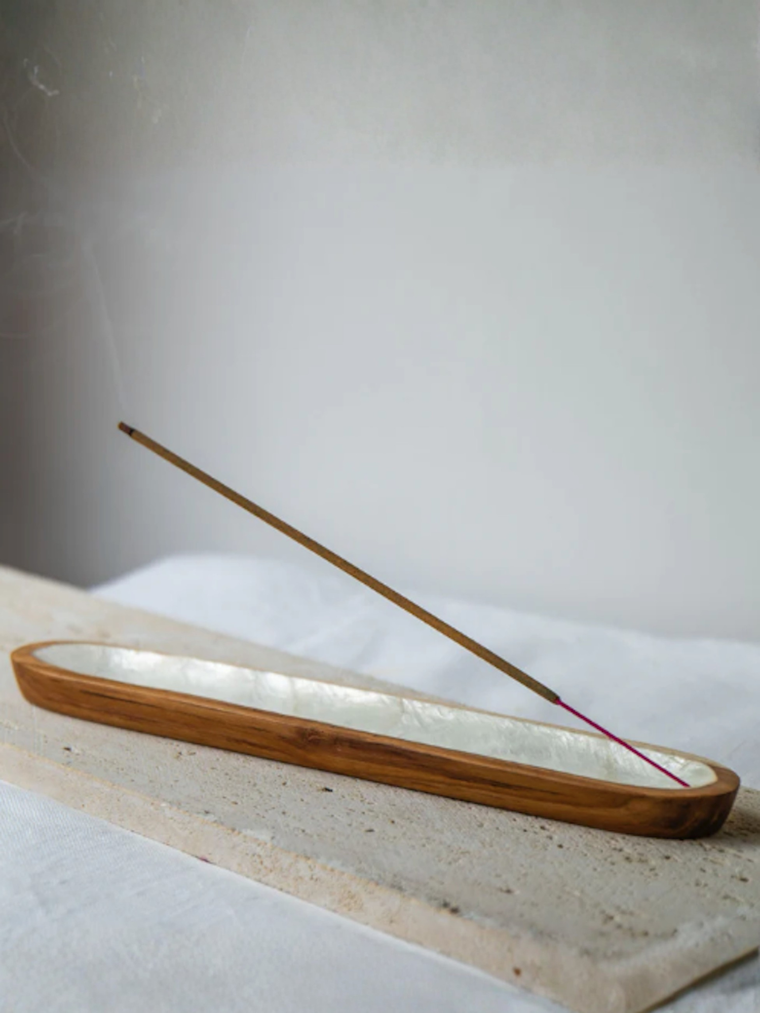 Wood and Shell incense burner with a single stick of incense on a light surface.