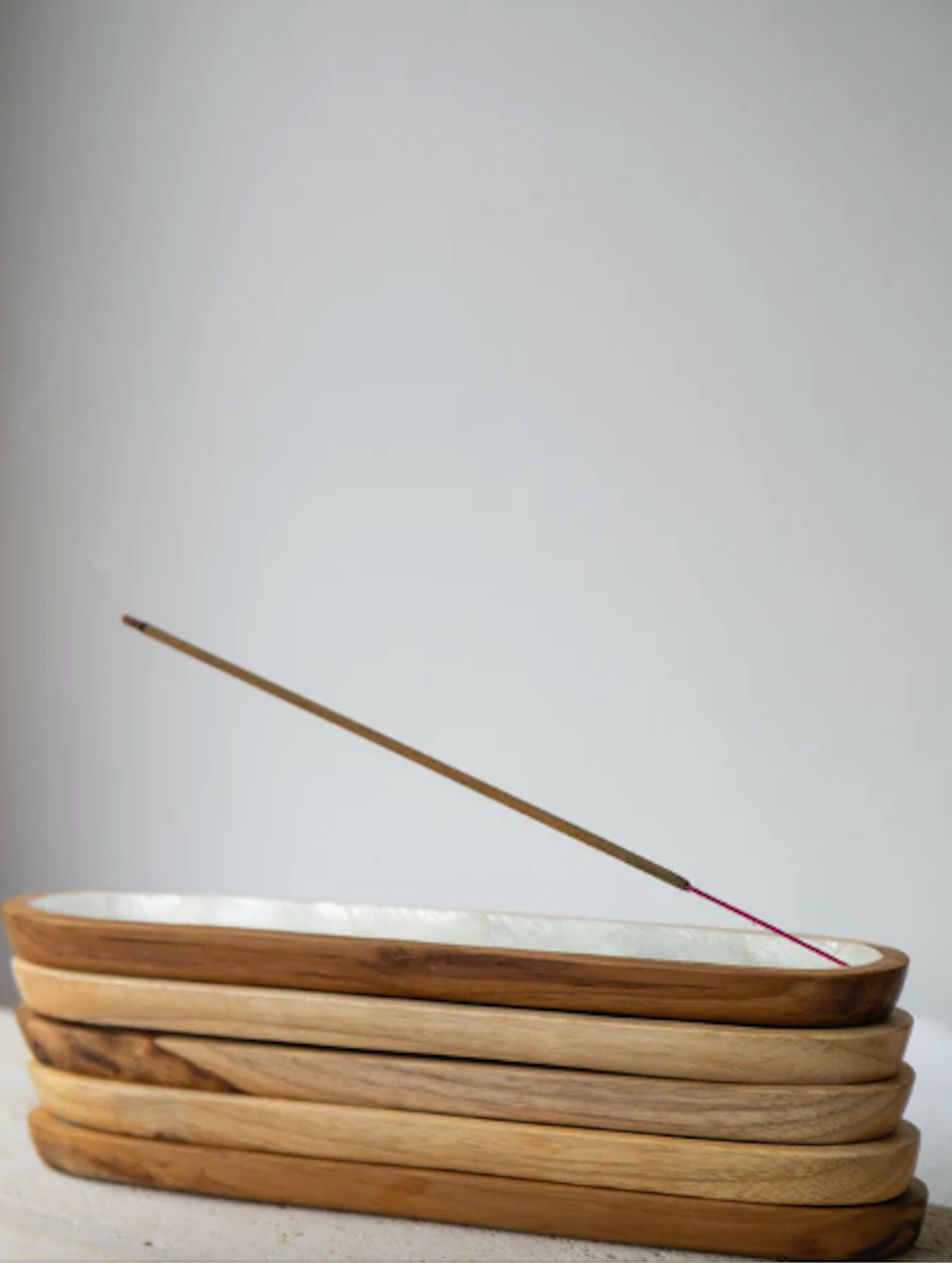 Wooden incense holder with a single incense stick on a white background