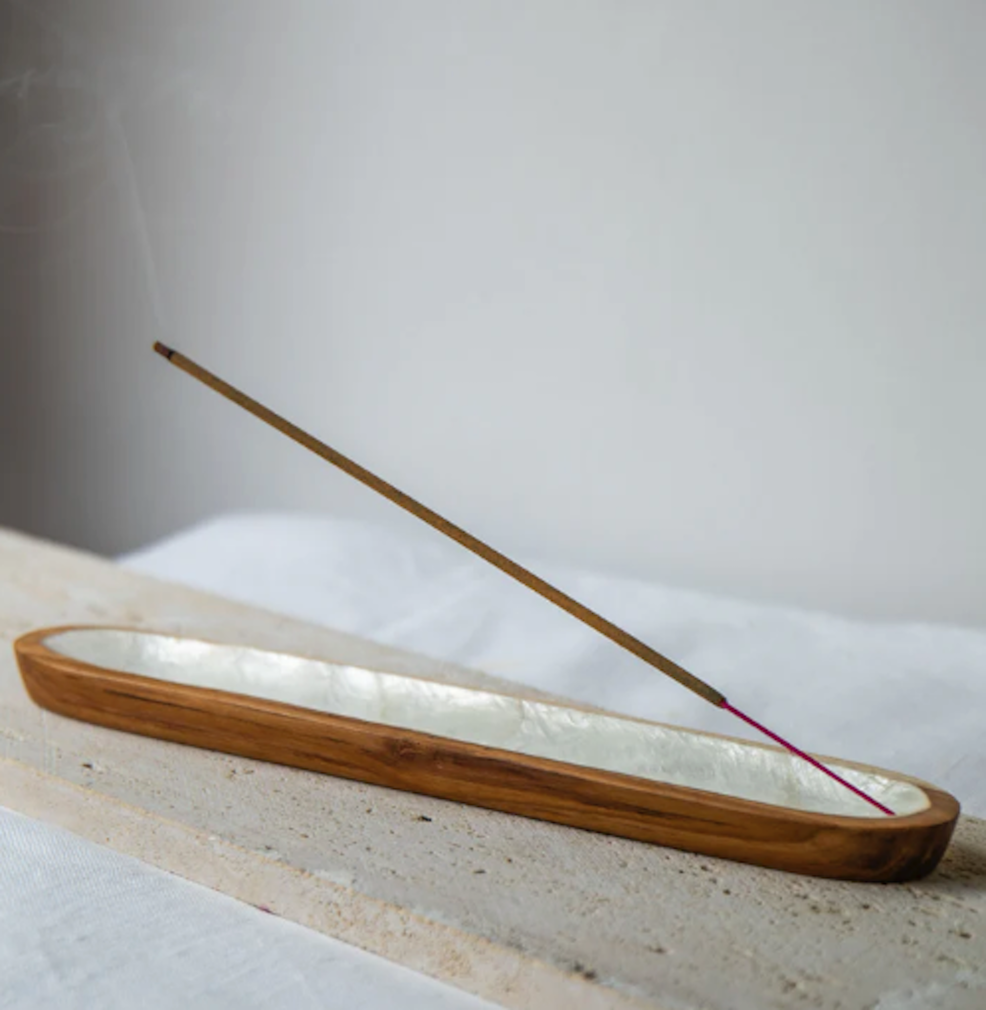 Wood and Shell incense burner with a single stick of incense on a light surface.
