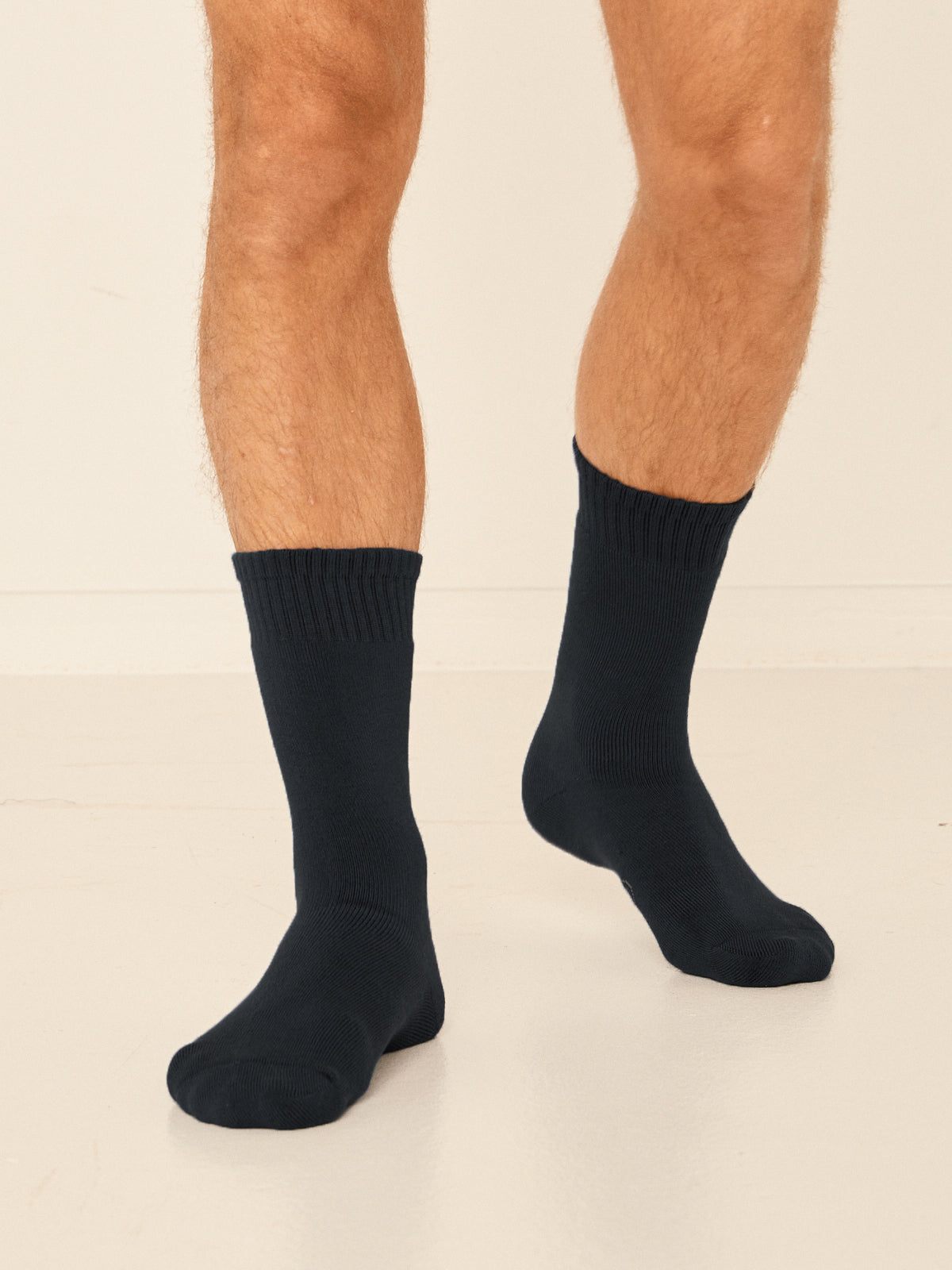 Model wearing black mid rise thick work, hiking, bed socks with ribbed top and thick cushioned sole, bamboo socks