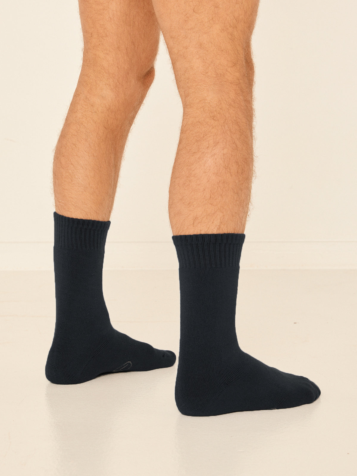 Model wearing black mid rise thick work, hiking, bed socks with ribbed top and thick cushioned sole, bamboo socks