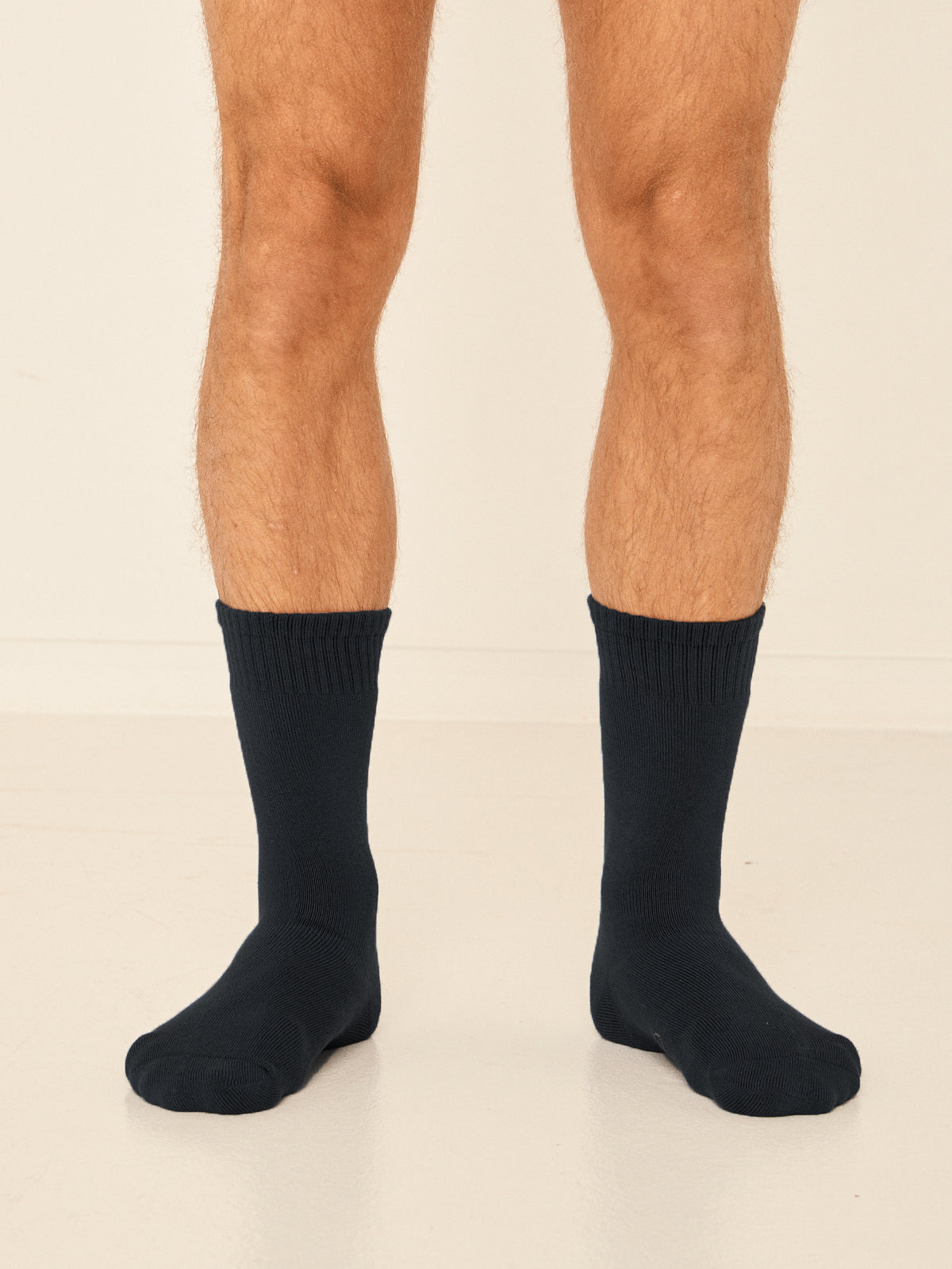 Model wearing black mid rise thick work, hiking, bed socks with ribbed top and thick cushioned sole, bamboo socks