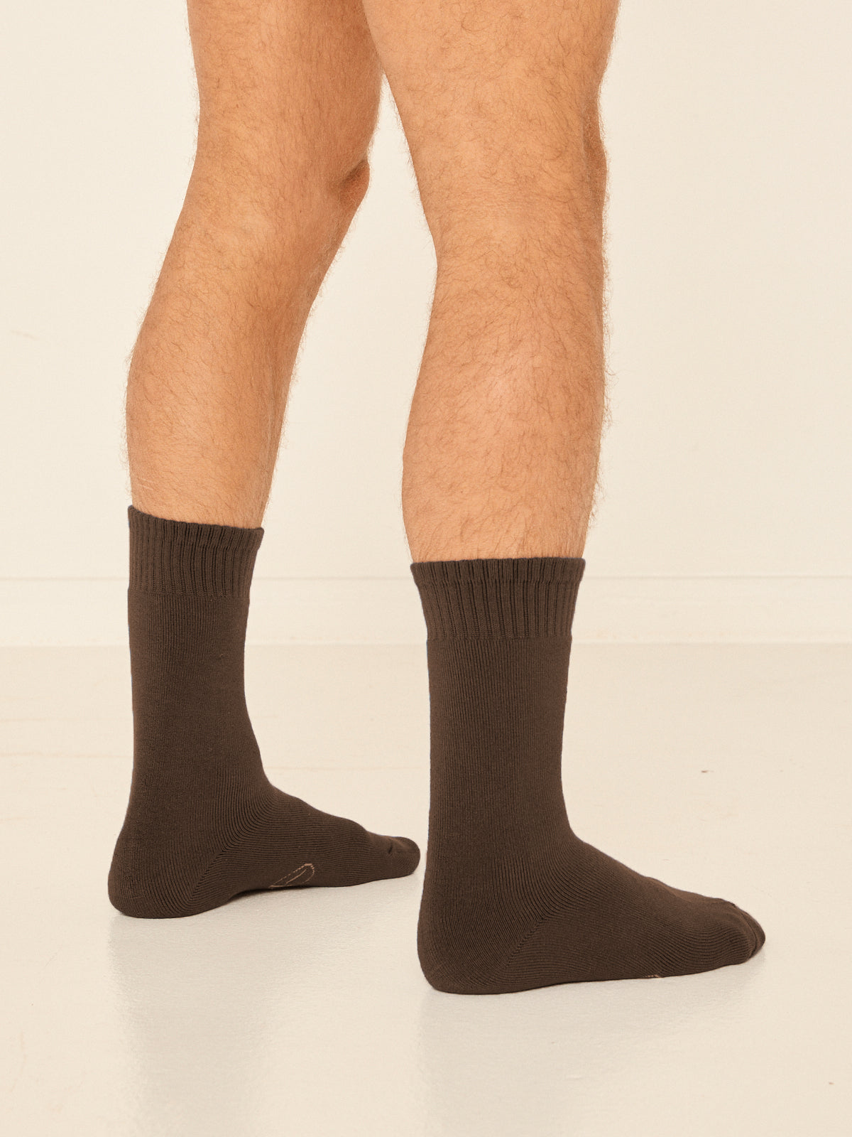 Model wearing cocoa brown mid rise thick work, hiking, bed socks with ribbed top and thick cushioned sole, bamboo socks