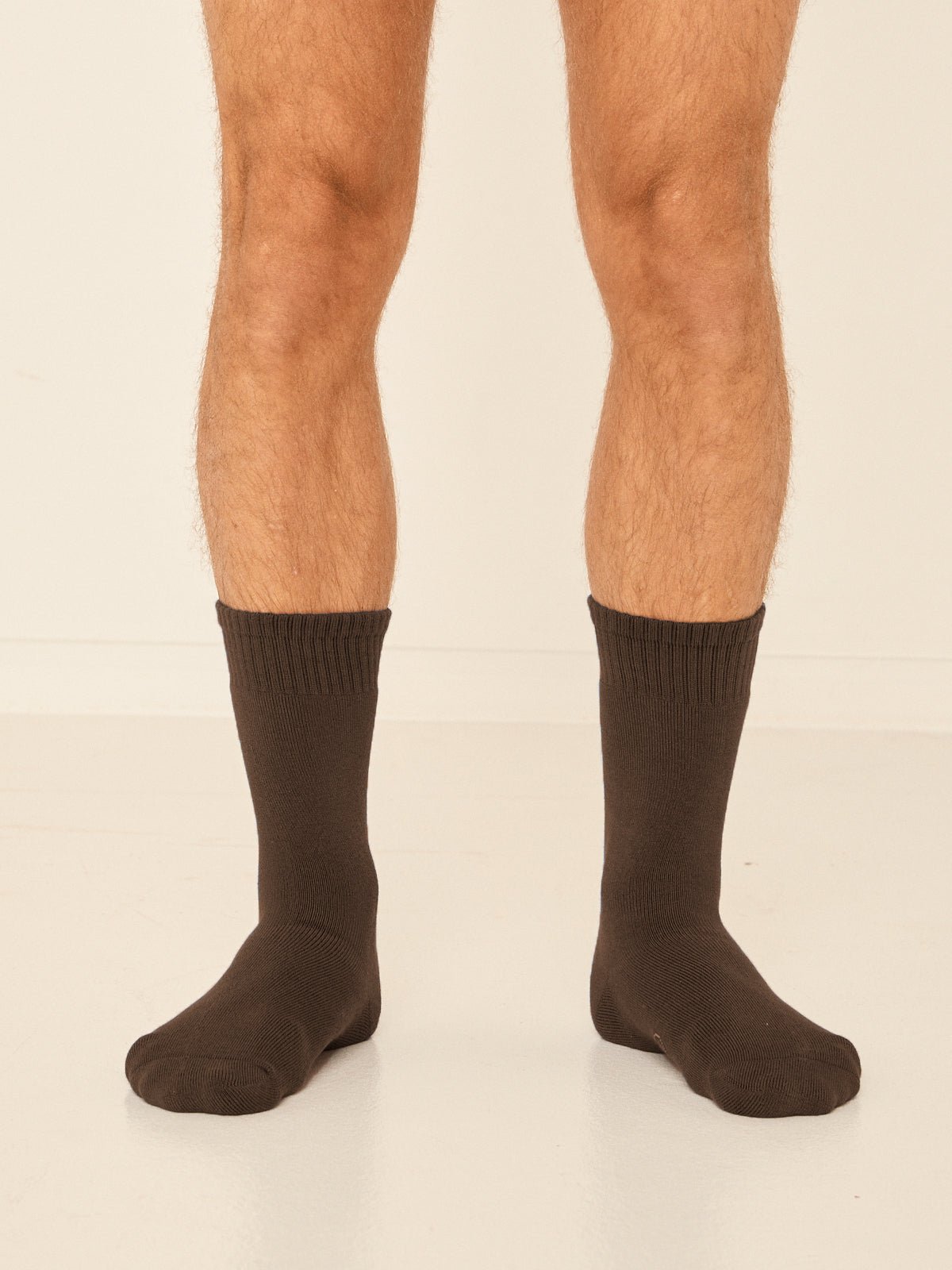 Model wearing cocoa brown mid rise thick work, hiking, bed socks with ribbed top and thick cushioned sole, bamboo socks
