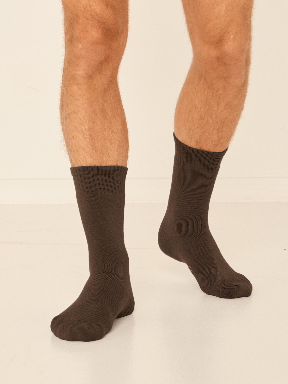 Model wearing cocoa brown mid rise thick work, hiking, bed socks with ribbed top and thick cushioned sole, bamboo socks