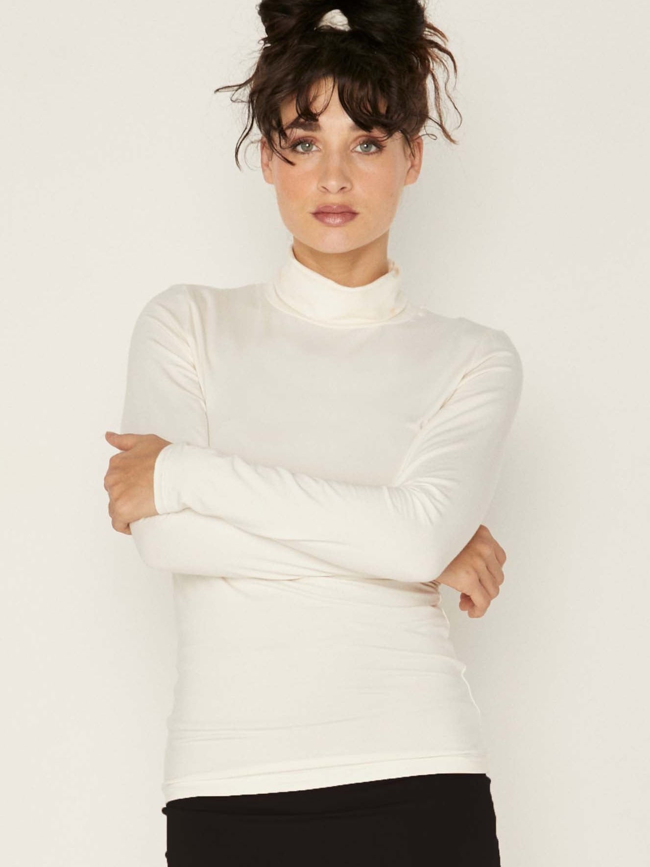 Model wearing cream high roll neck fitted skivvy, fitted long sleeves, women's bamboo clothing