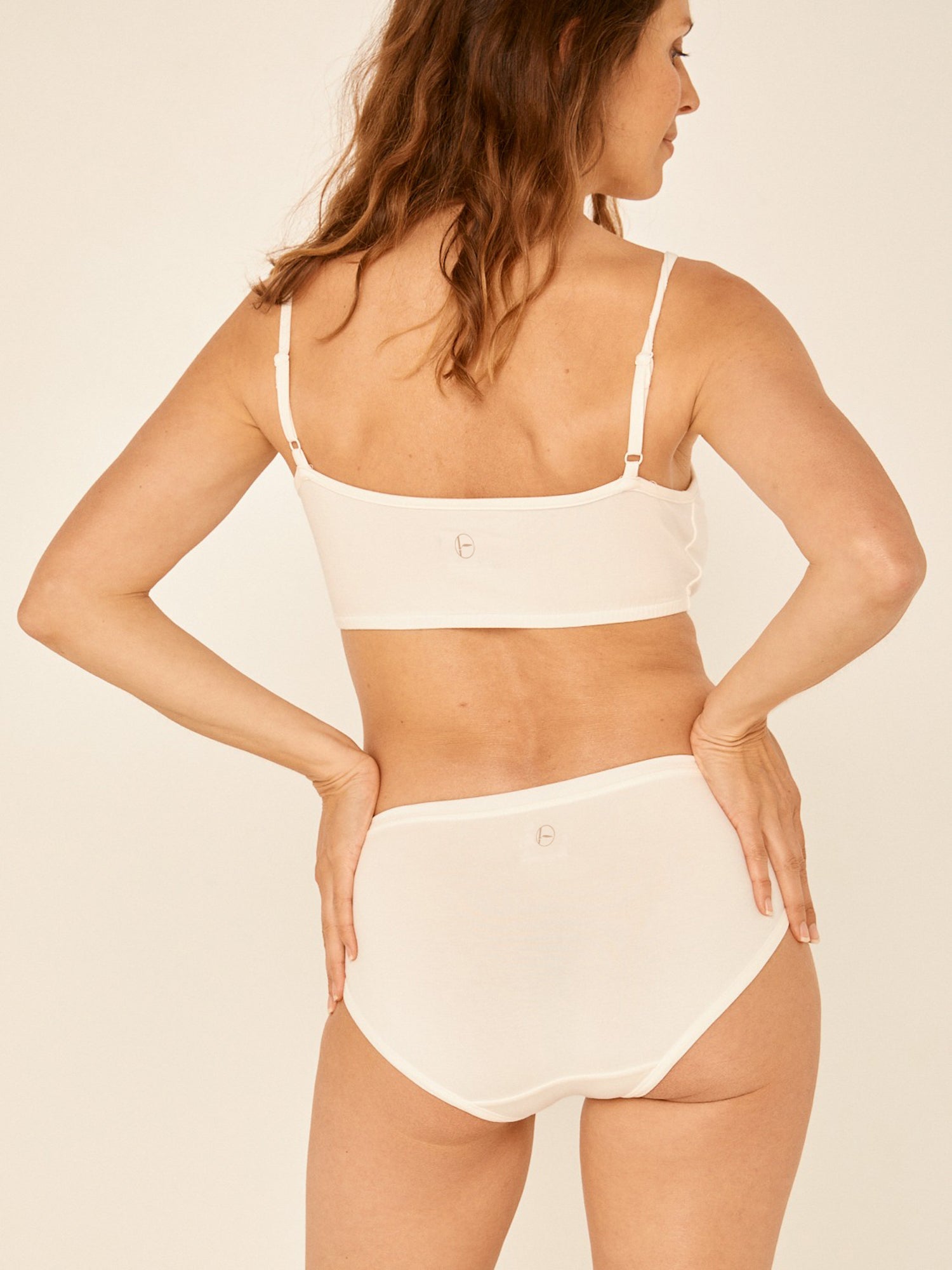 Model wearing a cream full brief with mid waist and soft leg banding to lift and shape bottom, women's bamboo underwear