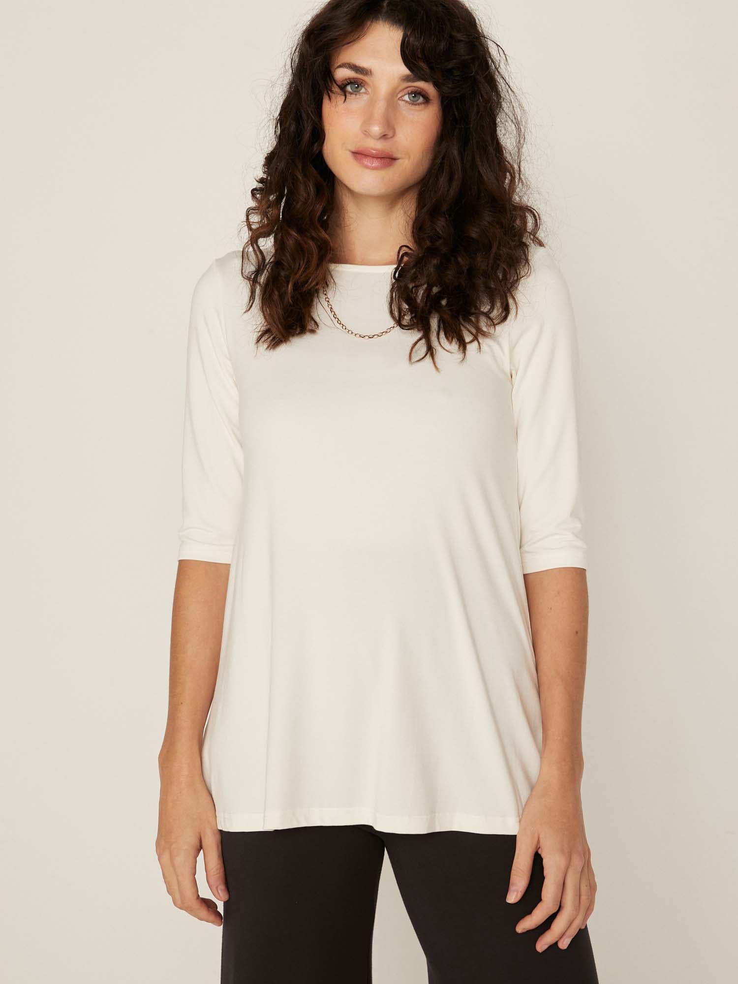 Model wearing a reversible cream mid sleeve t-shirt with scoop and boat necklines, a-line long line body, women's bamboo clothing