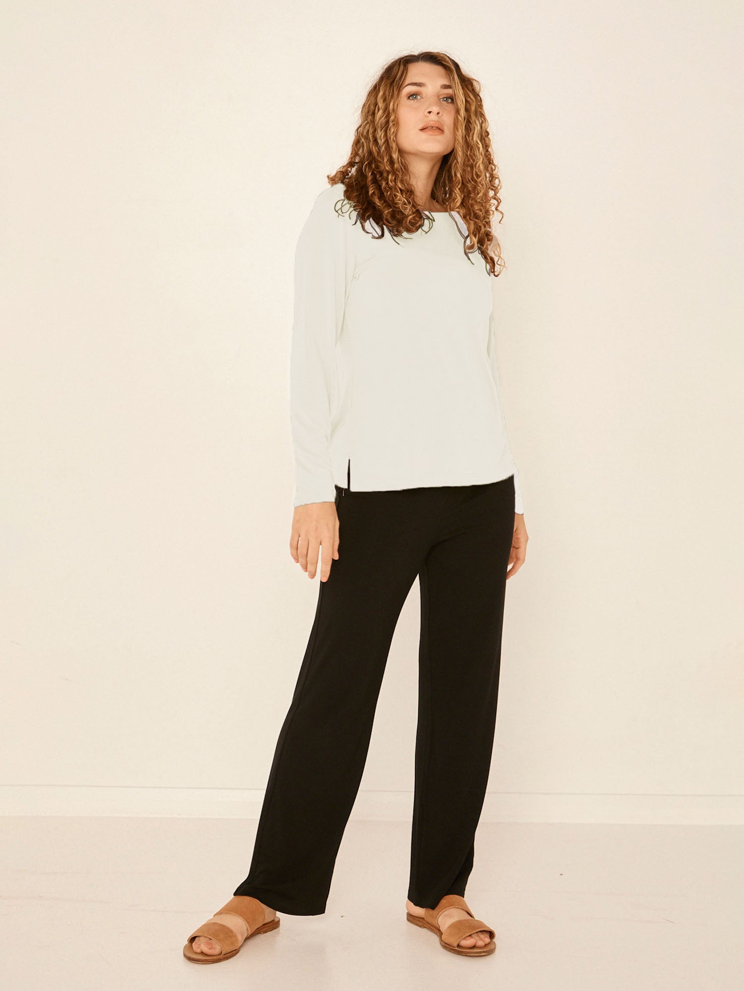 Model wearing a cream boat neck long sleeve t-shirt, fitted through shoulders and chest with loose fit to waist, women's bamboo clothing
