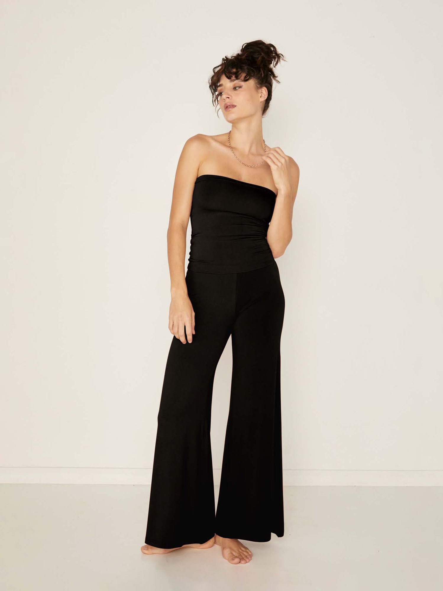 Model wearing black full length palazzo pants, fitted waist and hips with flowing wide leg, adjustable high waistband, women's bamboo clothing