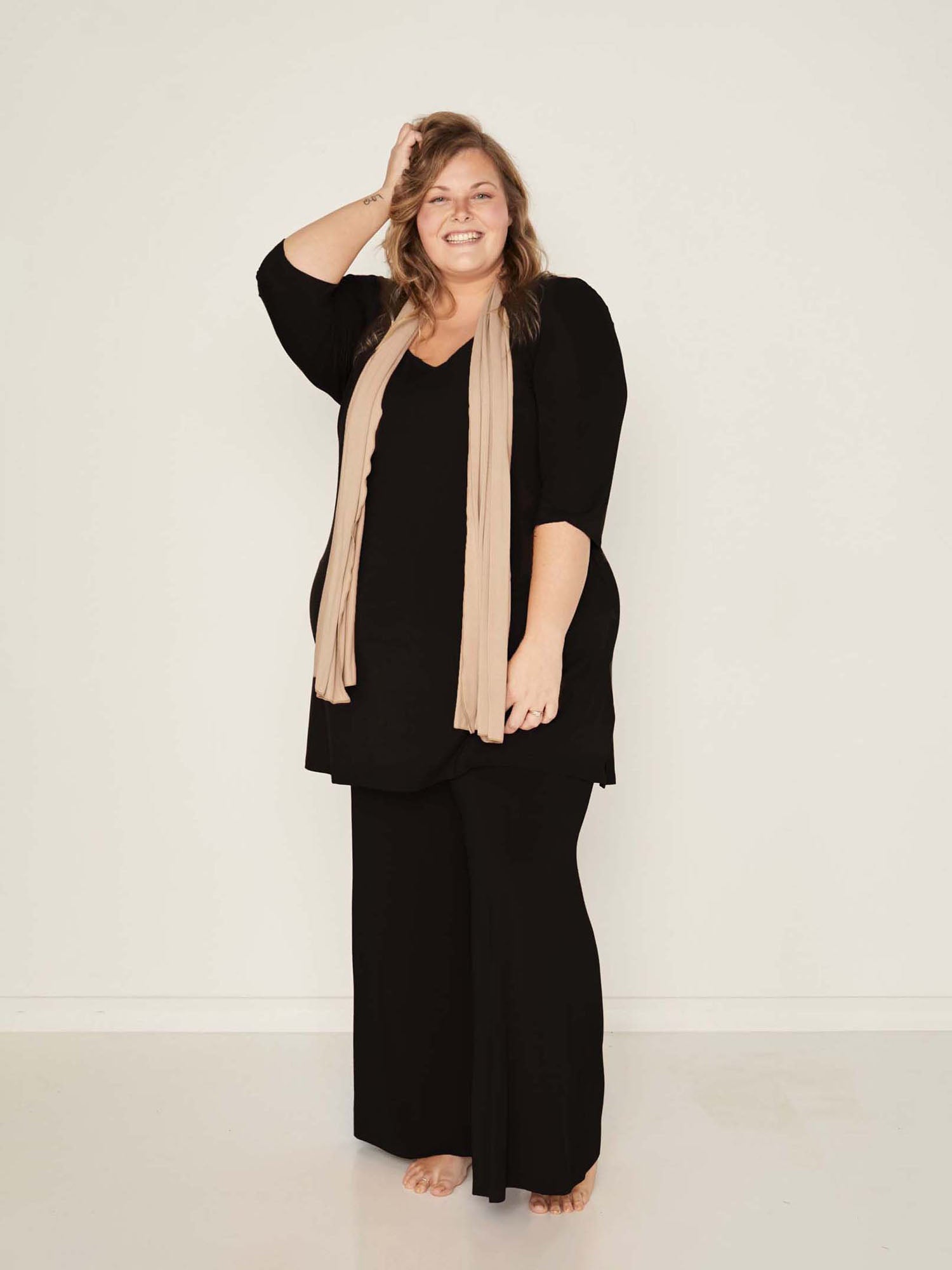 Model wearing black full length palazzo pants, fitted waist and hips with flowing wide leg, adjustable high waistband, women's bamboo clothing