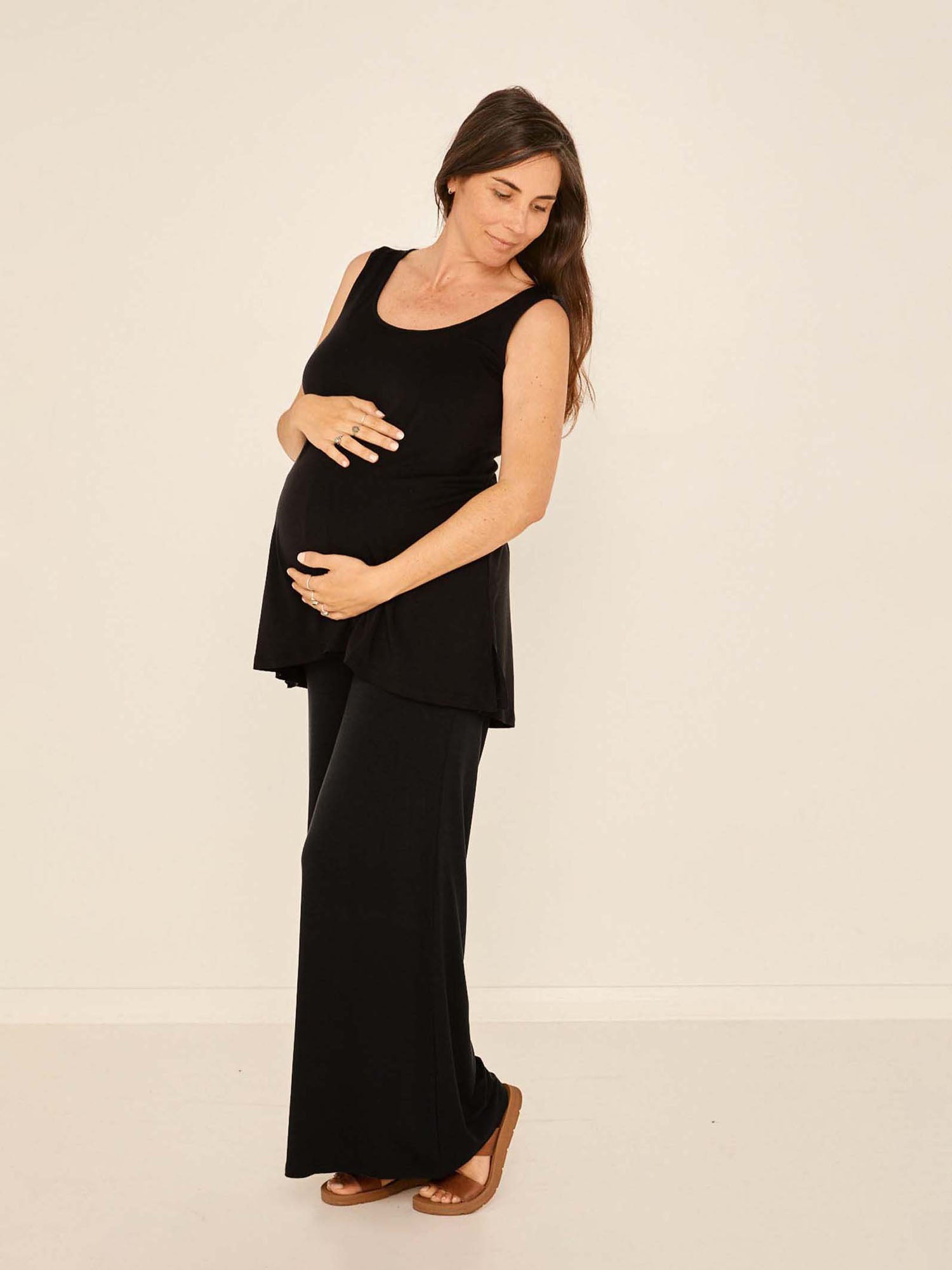 Model wearing black full length palazzo pants, fitted waist and hips with flowing wide leg, adjustable high waistband, women's bamboo clothing