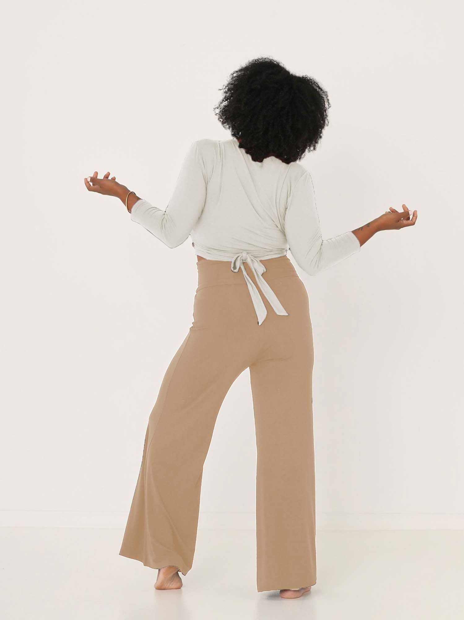 Model wearing caramel full length palazzo pants, fitted waist and hips with flowing wide leg, adjustible high waistband, women's bamboo clothing
